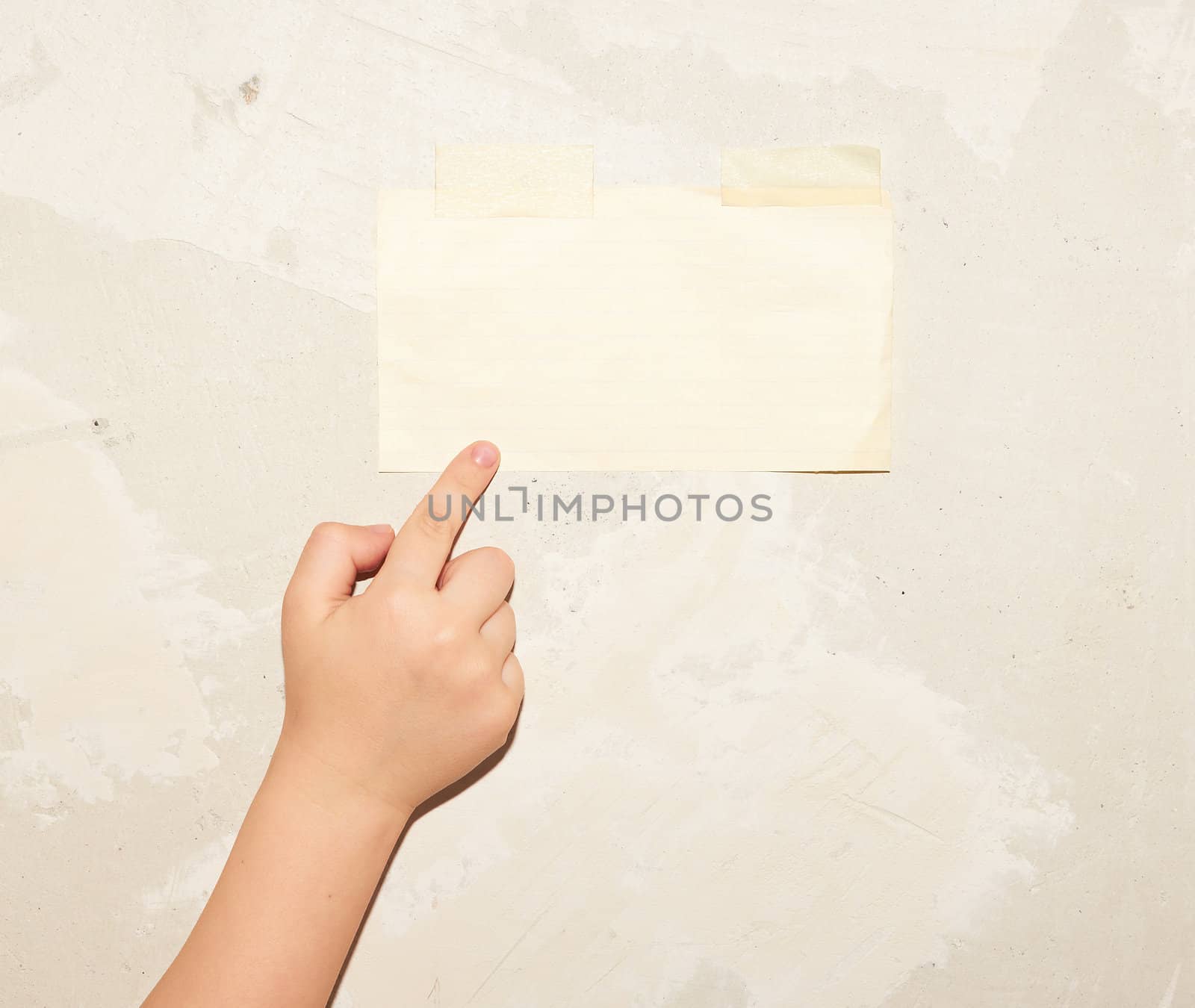 Child's hand pointing to the sheet of paper on the wall