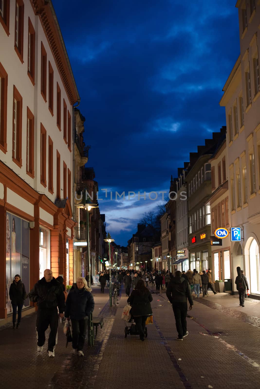 Heidelberg, Germany - February 2, 2013: Tourists walking through the centre of Heidelberg, Germany with its beautiful medieval houses in the evening of February 2, 2013. Heidelberg is a well-known tourist attraction due to its old history and beautiful location at the Neckar river.