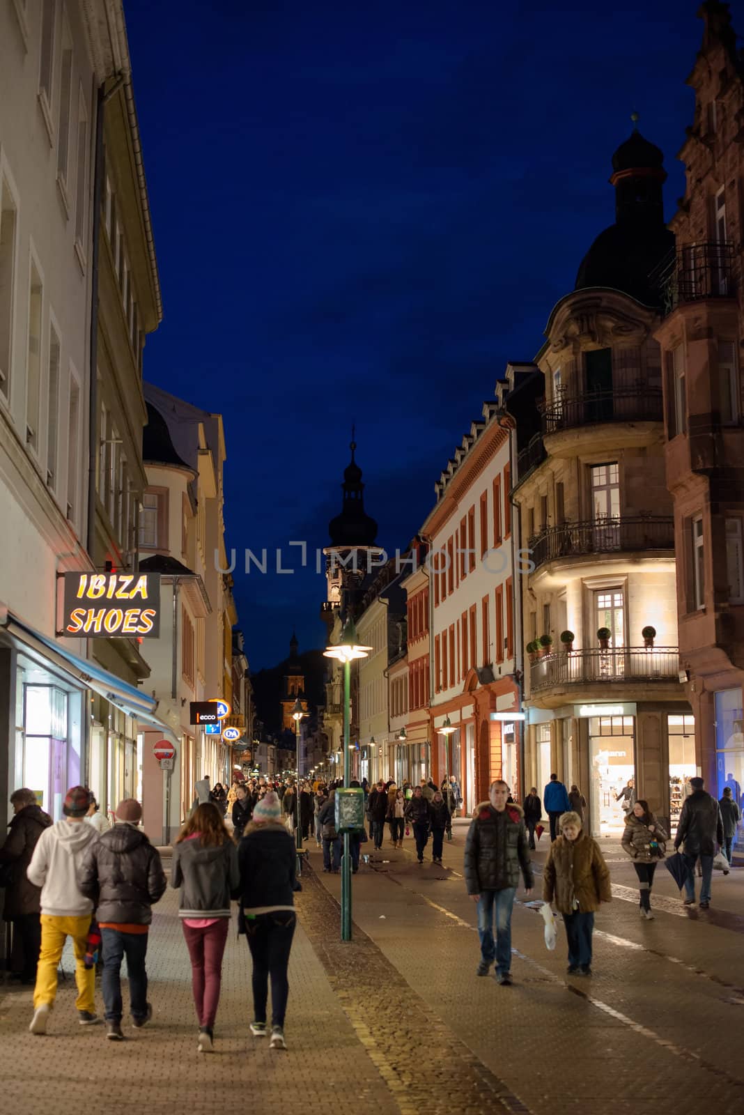 Heidelberg, Germany - February 2, 2013: Tourists walking through the centre of Heidelberg, Germany with its beautiful medieval houses in the evening of February 2, 2013. Heidelberg is a well-known tourist attraction due to its old history and beautiful location at the Neckar river.