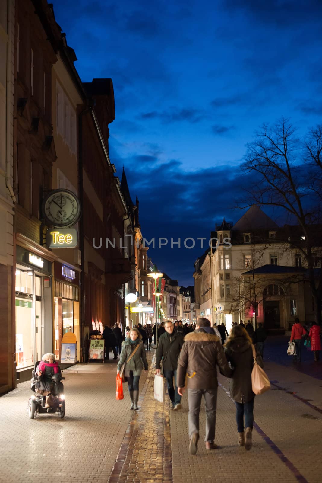 Heidelberg, Germany - February 2, 2013: Tourists walking through the centre of Heidelberg, Germany with its beautiful medieval houses in the evening of February 2, 2013. Heidelberg is a well-known tourist attraction due to its old history and beautiful location at the Neckar river.