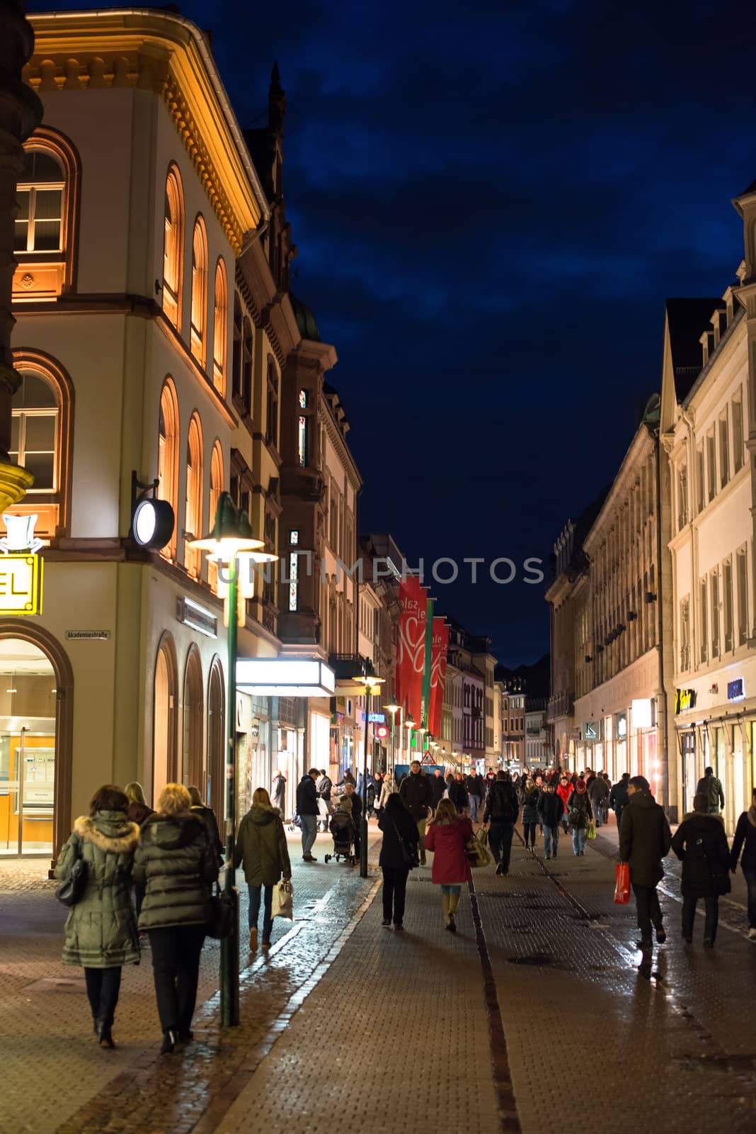 Heidelberg, Germany - February 2, 2013: Tourists walking through the centre of Heidelberg, Germany with its beautiful medieval houses in the evening of February 2, 2013. Heidelberg is a well-known tourist attraction due to its old history and beautiful location at the Neckar river.