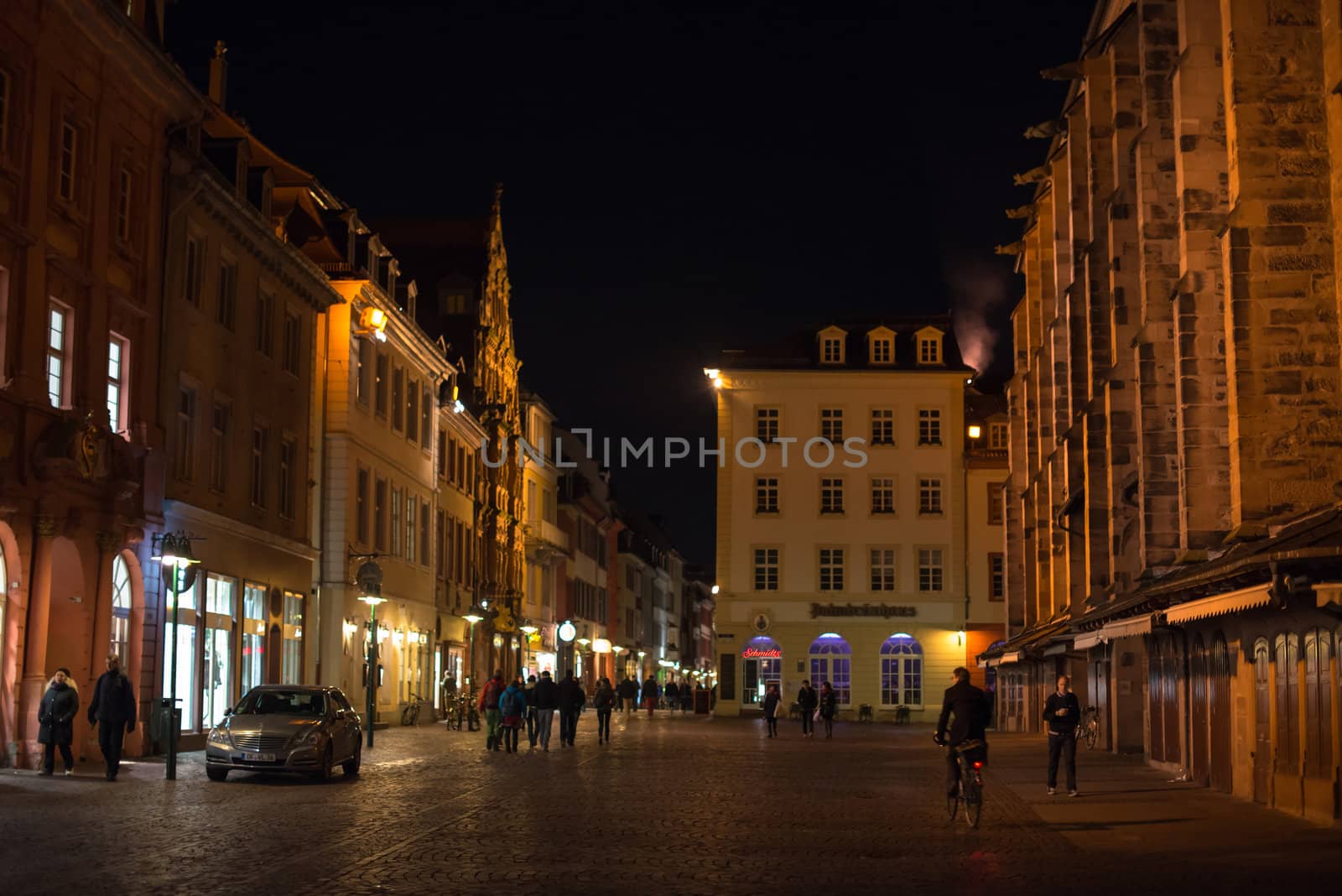 Heidelberg, Germany - February 2, 2013: Tourists walking through the centre of Heidelberg, Germany with its beautiful medieval houses in the evening of February 2, 2013. Heidelberg is a well-known tourist attraction due to its old history and beautiful location at the Neckar river.