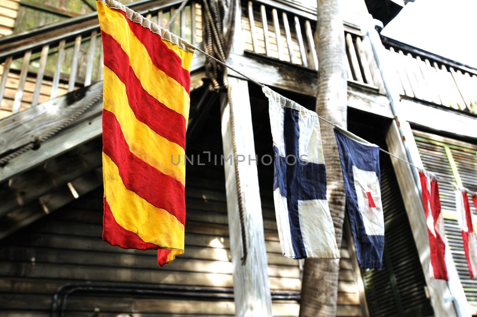 weathered and colorful flags hanging from clothesline near wooden building