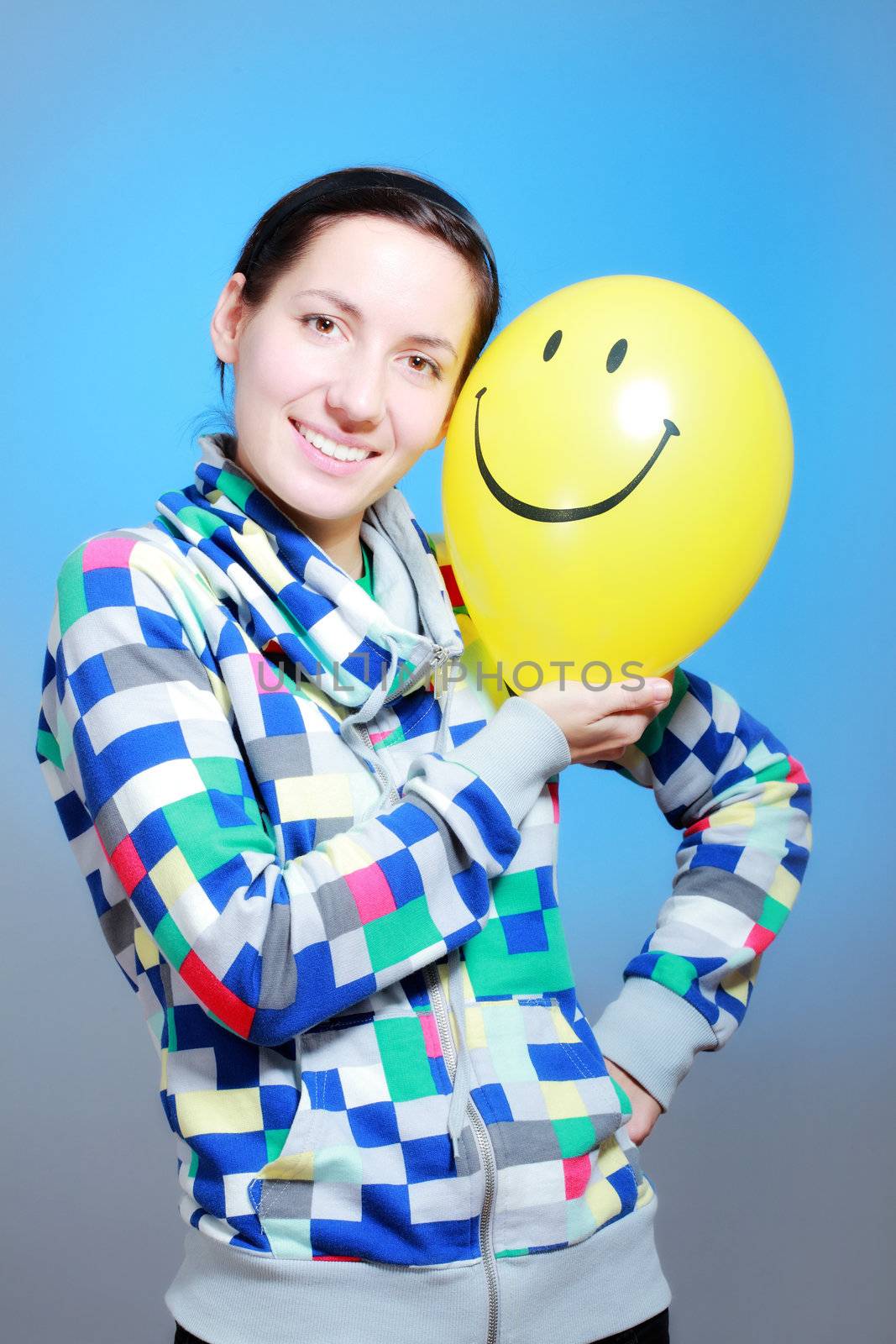 girl with a yellow smiley balloon against blue