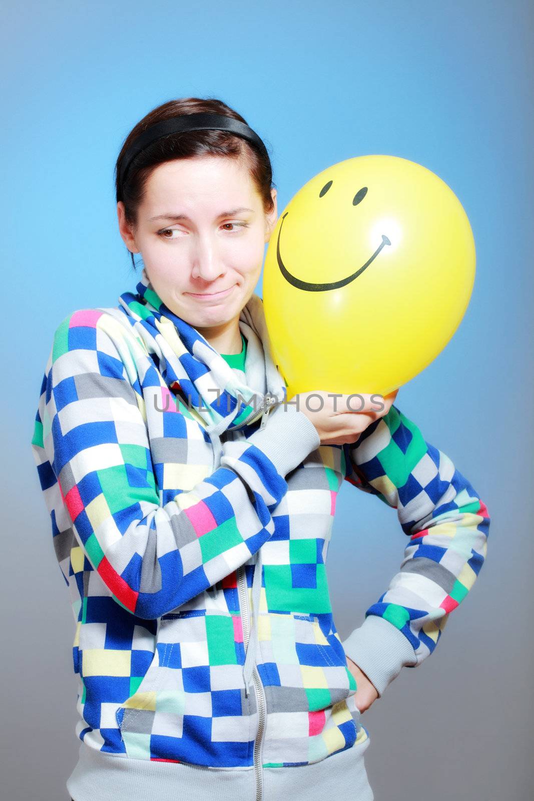 girl with a yellow smiley balloon against blue