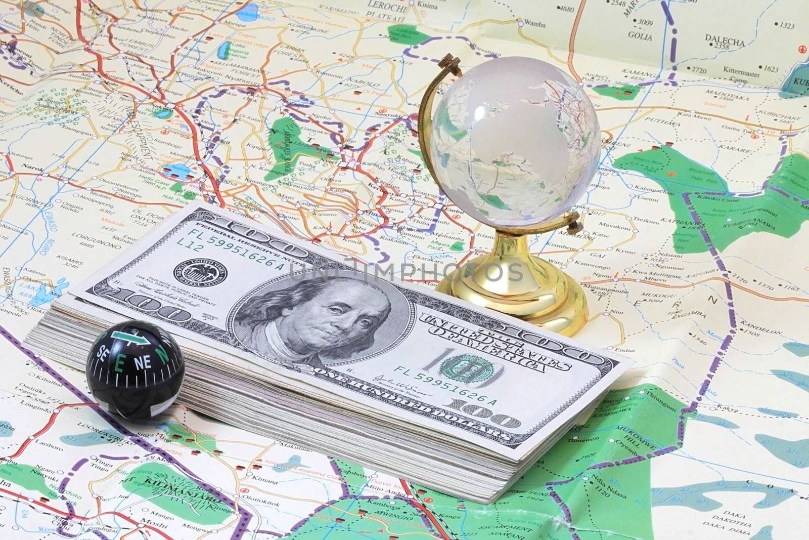 A few dollars lying on the map, with glass globe and compass