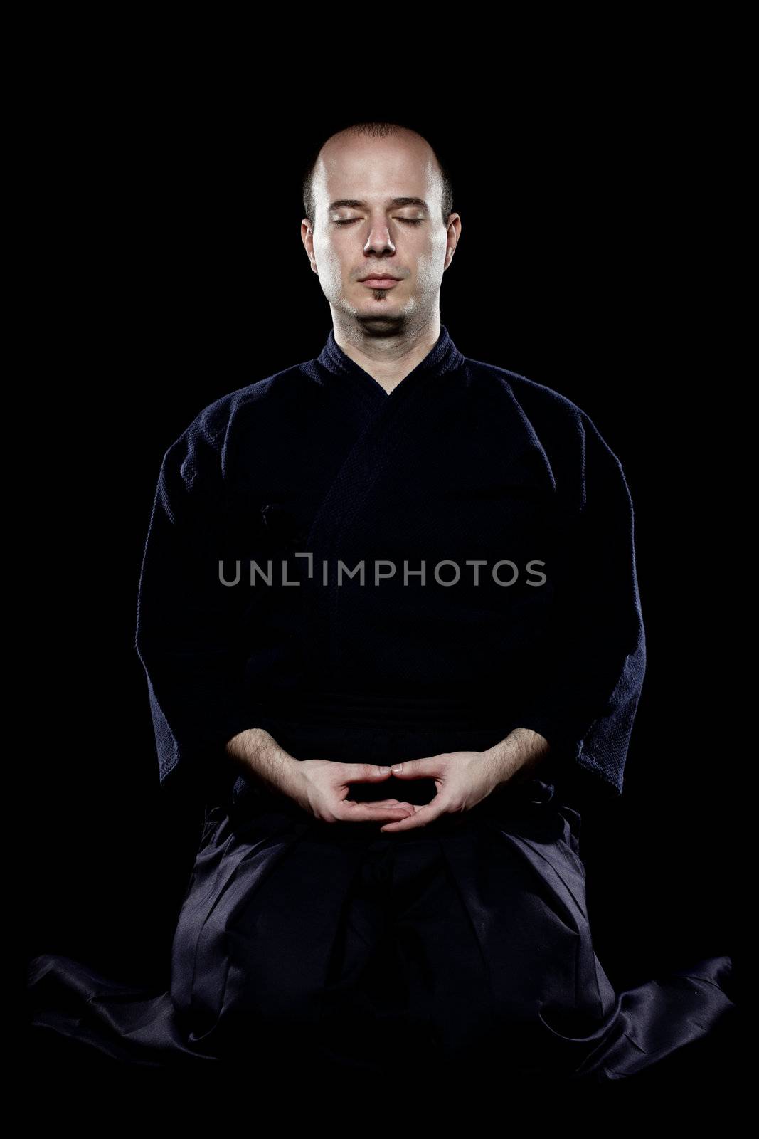 portrait of a kendo fighter meditating, against black backgroung