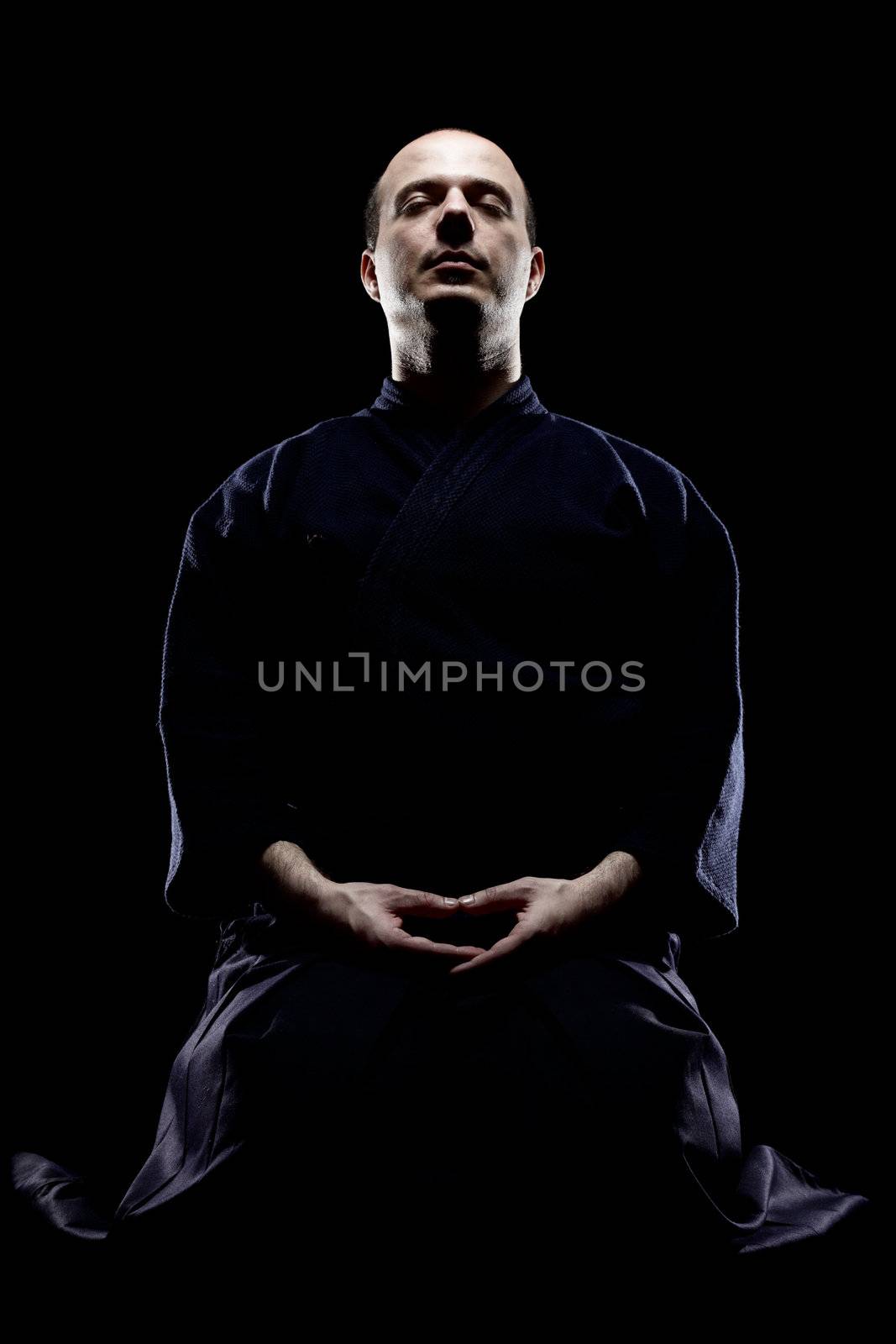 portrait of a kendo fighter meditating, against black backgroung