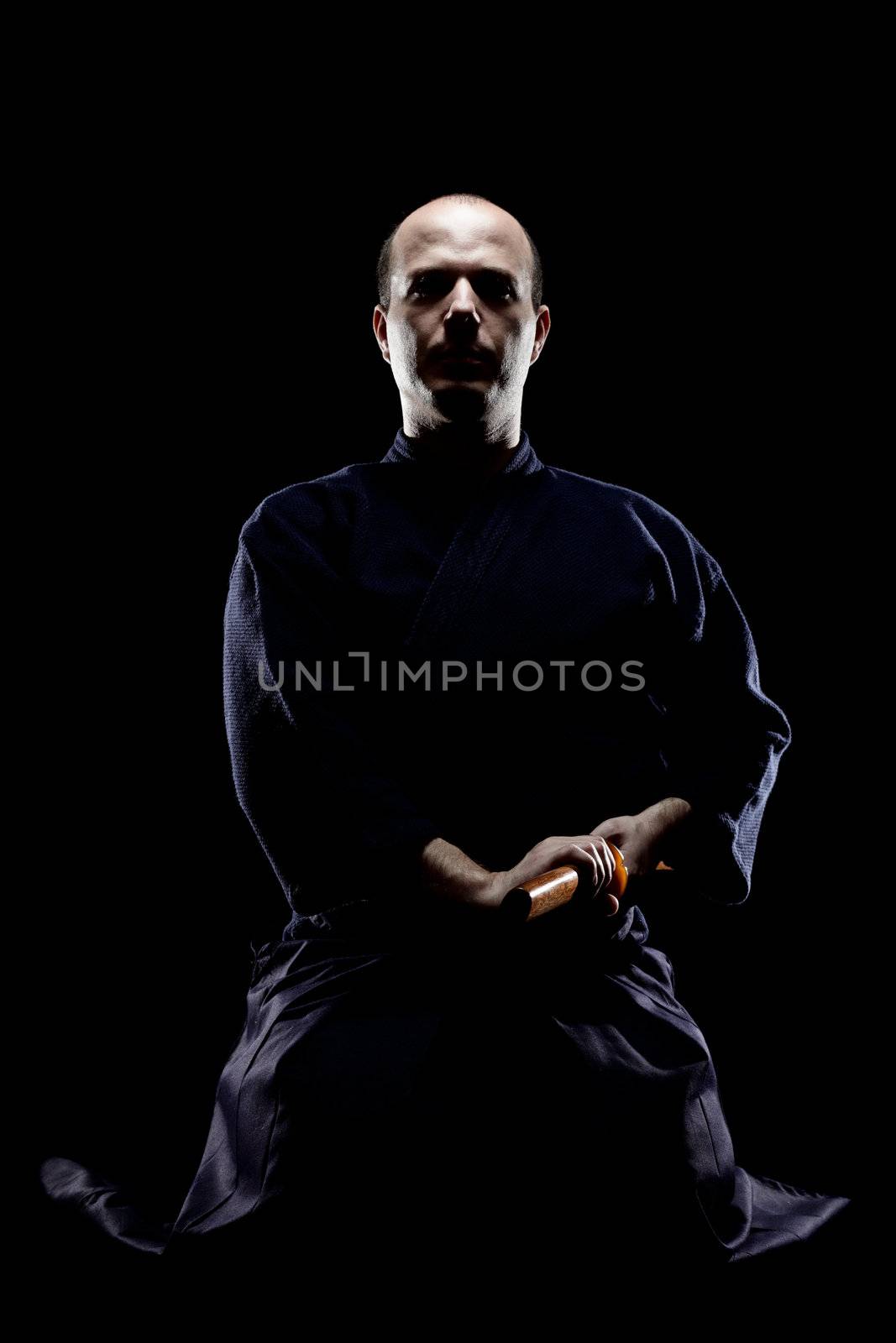 portrait of a kendo fighter with bokken, against black backgroung