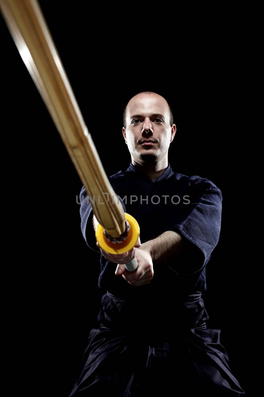 portrait of a kendo fighter with shinai, against black backgroung