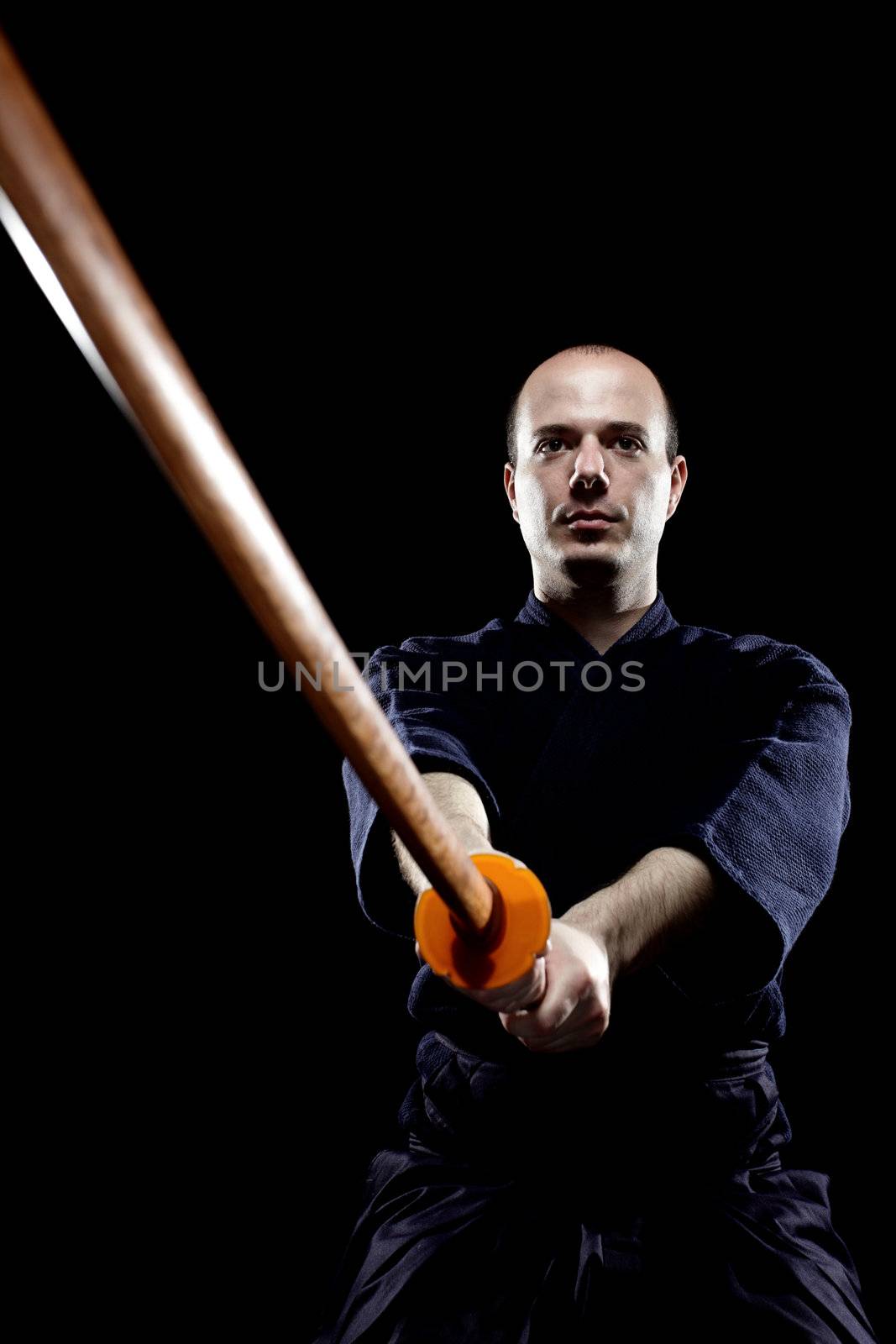 portrait of a kendo fighter with bokken, against black backgroung