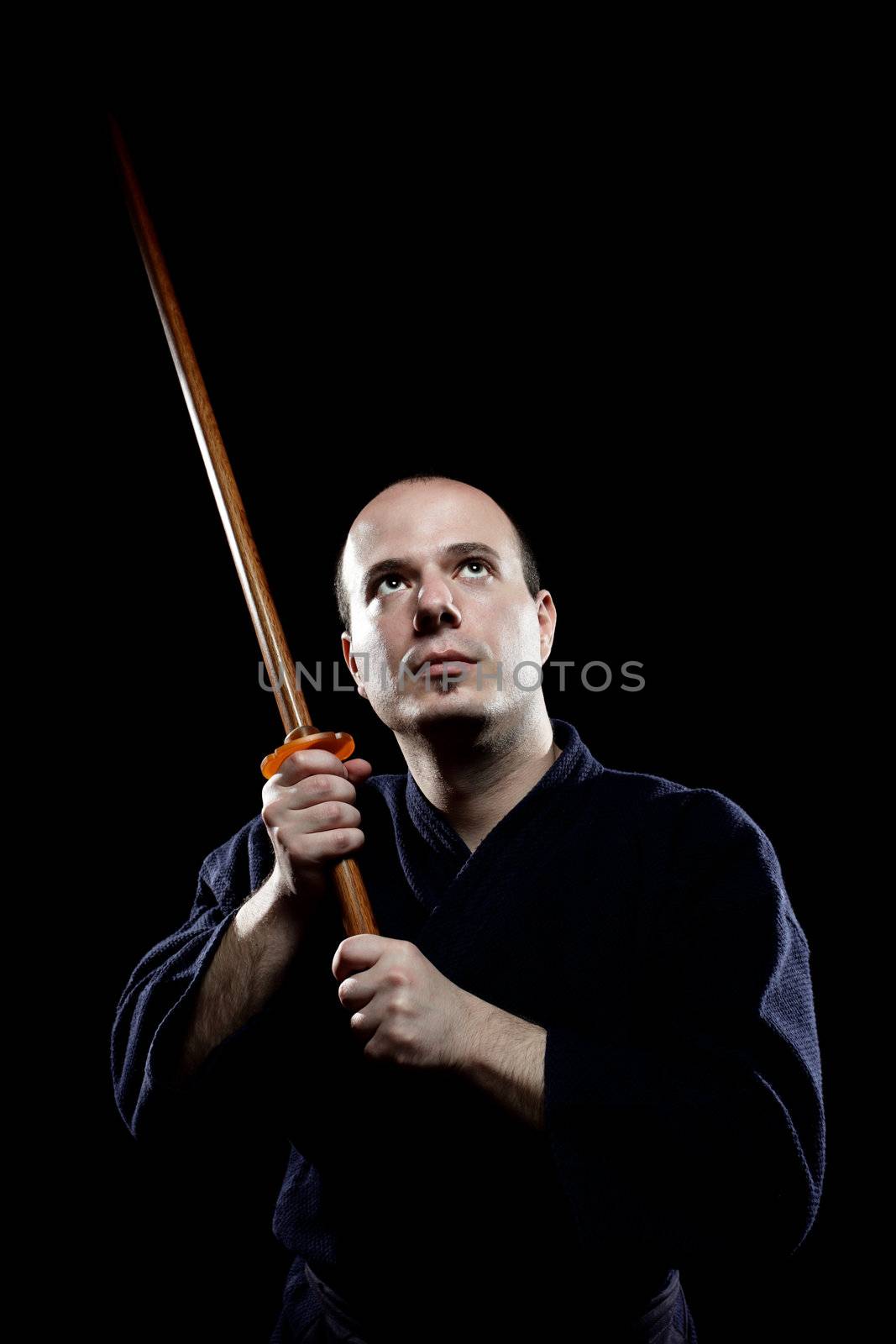 portrait of a kendo fighter with bokken, against black backgroung