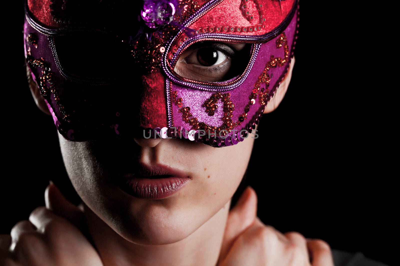 Elegant young girl with carnival mask against black background