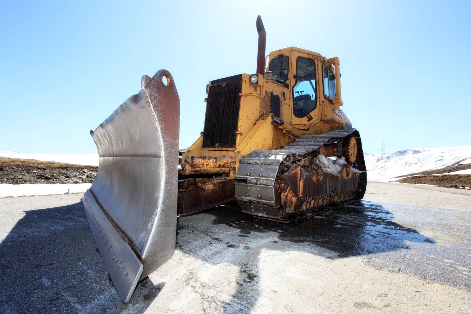 snow cleaning bulldozer on a mountain road in spring