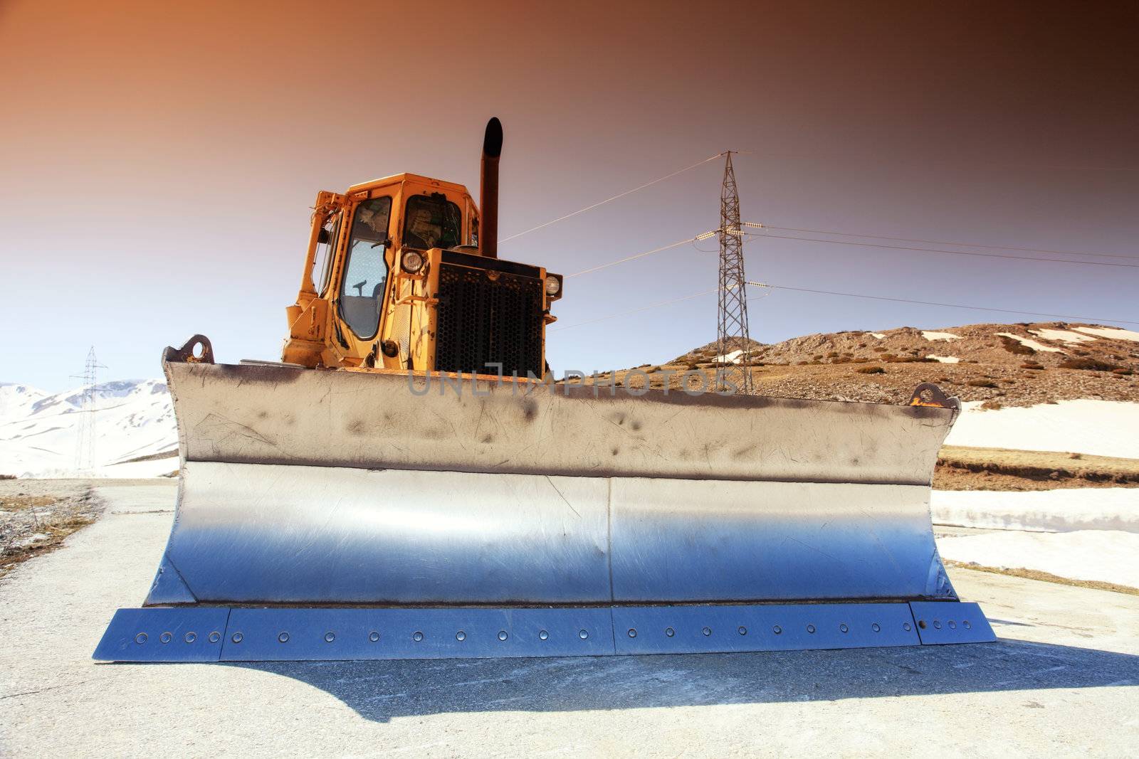 snow cleaning bulldozer on a mountain road in spring