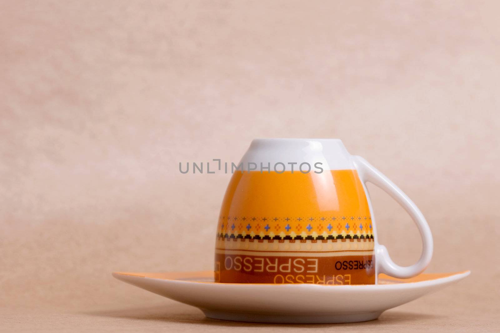 orange espresso cup on ochre background