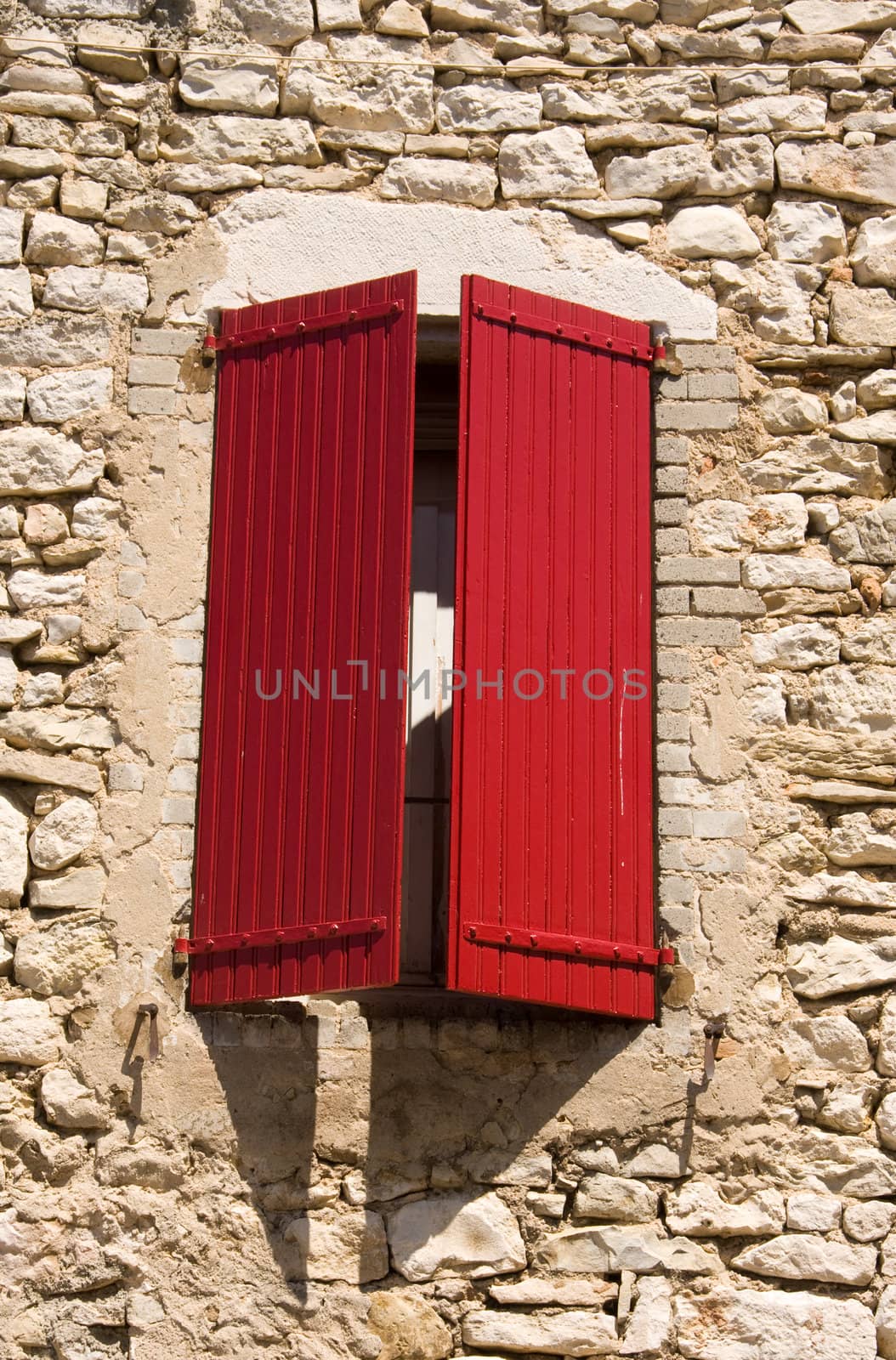 stone wall with window and red typical french shutters