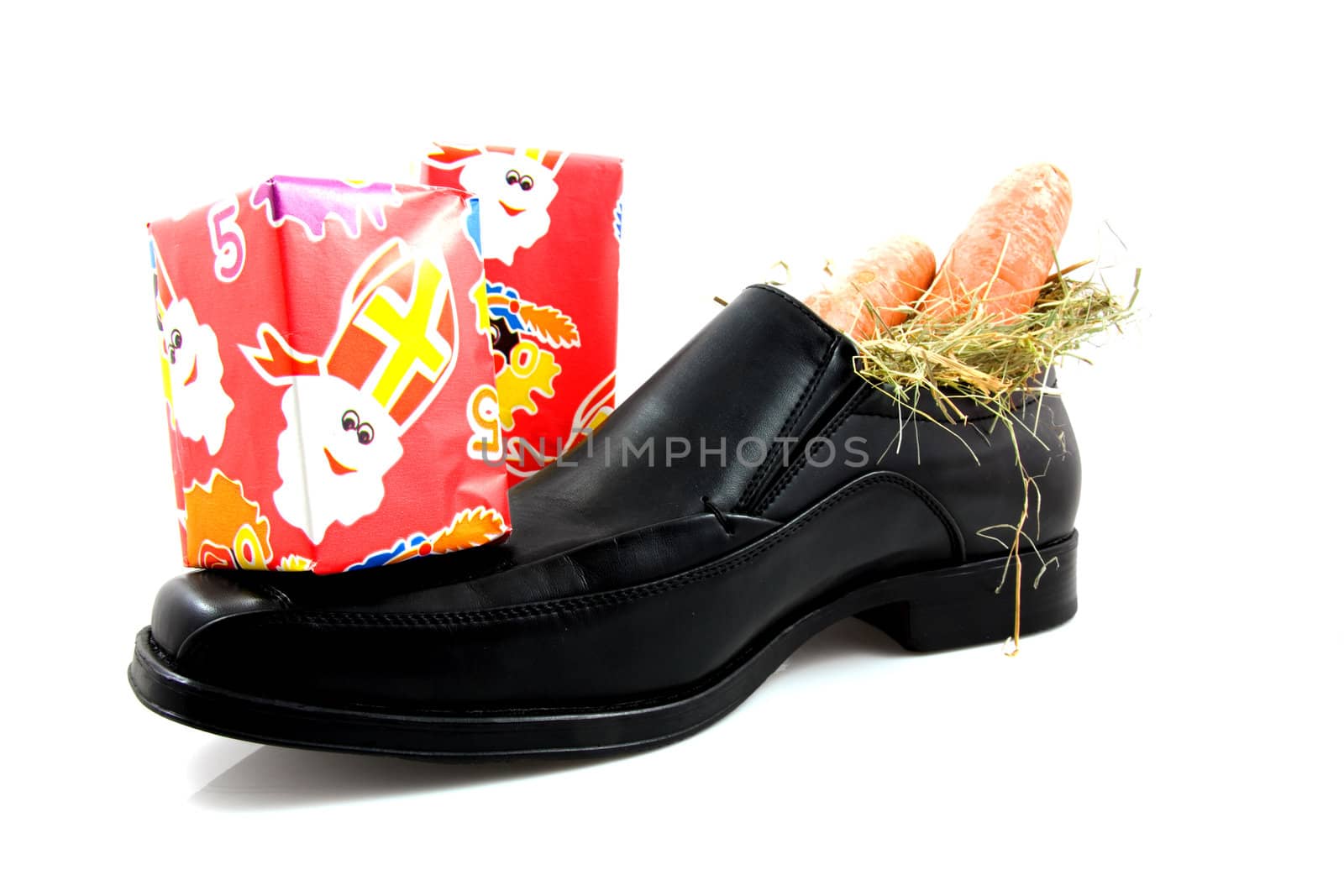 Big black men shoe with carrots and presents for typical Dutch Sinterklaas, over white background