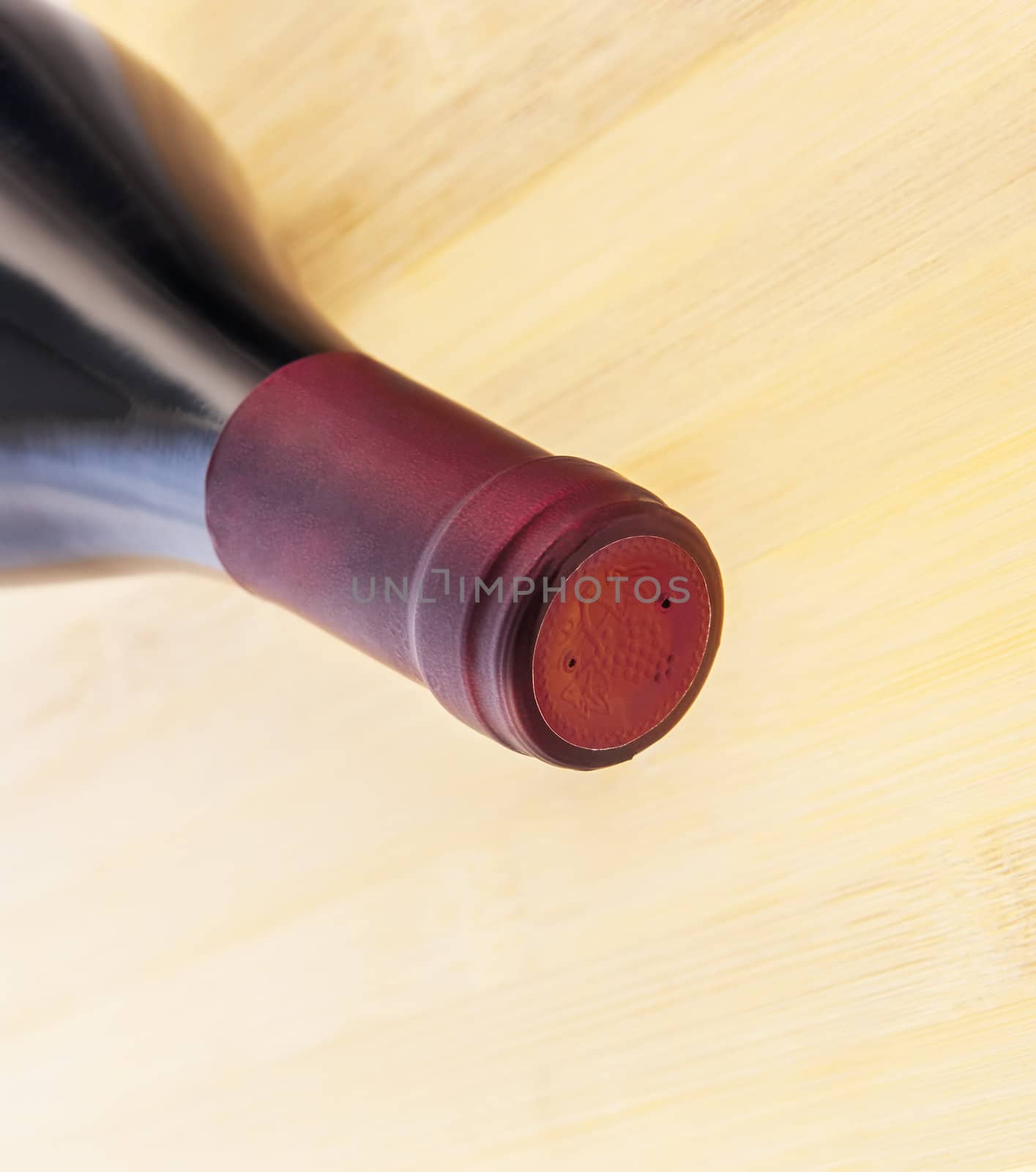 Red wine bottle on wooden table background by Zhukow