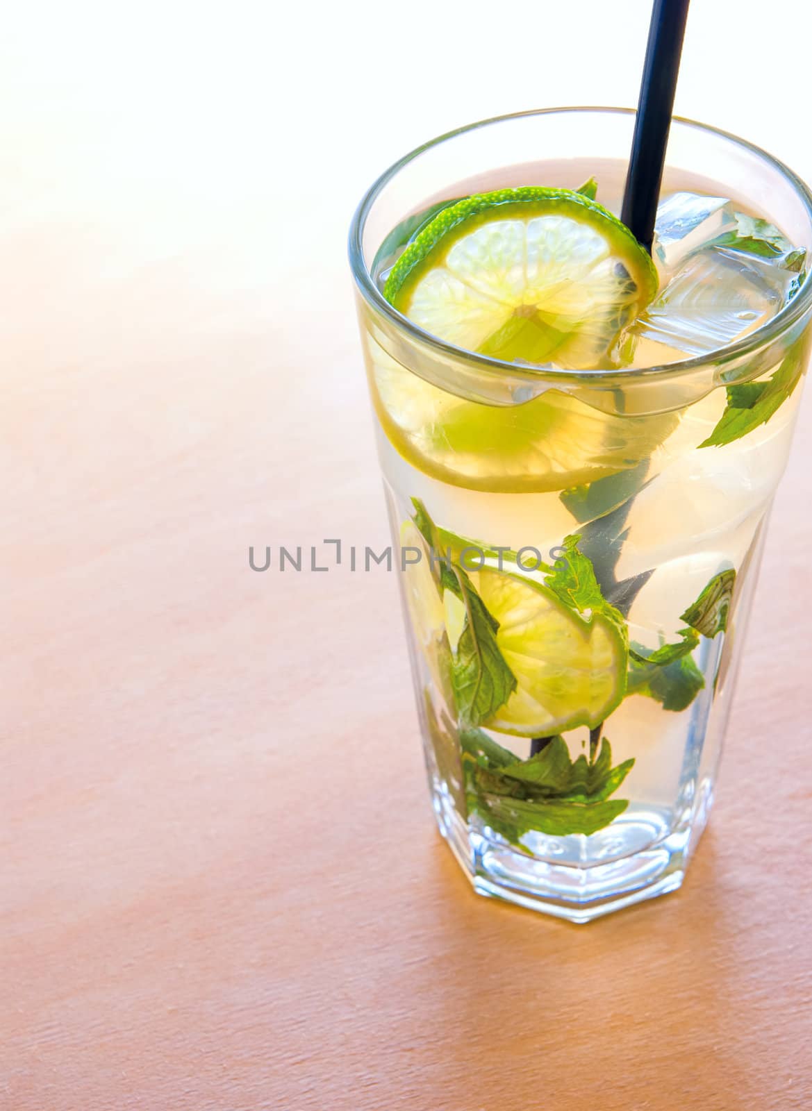 mojito cocktails with lime, mint leaves and ice on wooden placemat background