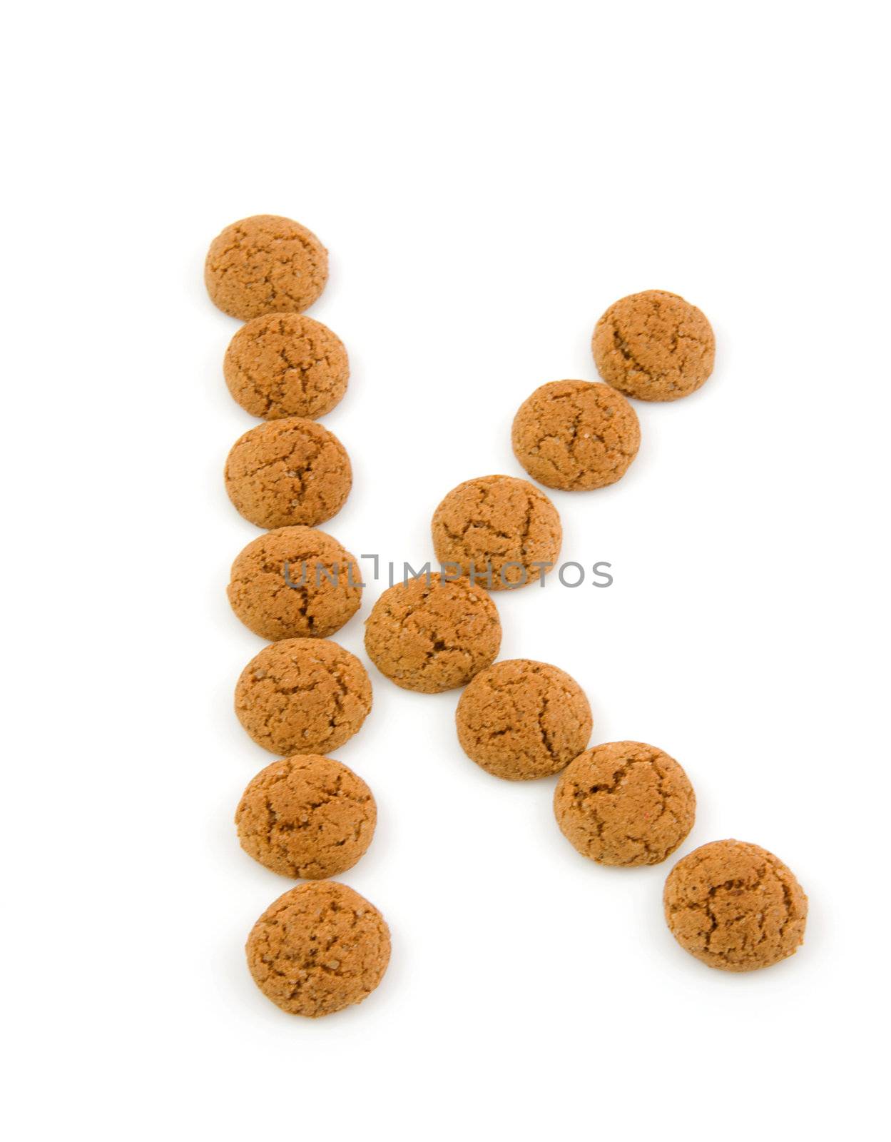 Ginger nuts, pepernoten, in the shape of letter K isolated on white background. Typical Dutch candy for Sinterklaas event in december.