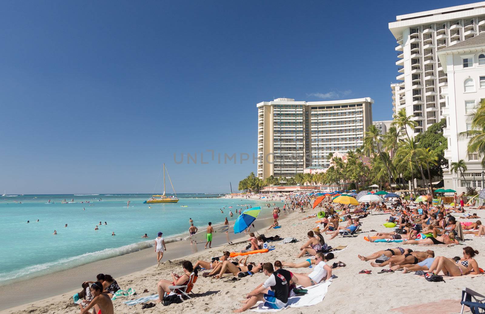 WAIKIKI, HI - JANUARY 20: Tourists sunbathe on busy Hawaii beach on 20 January 2012. The Waikiki Beach restoration project was completed early 2012.