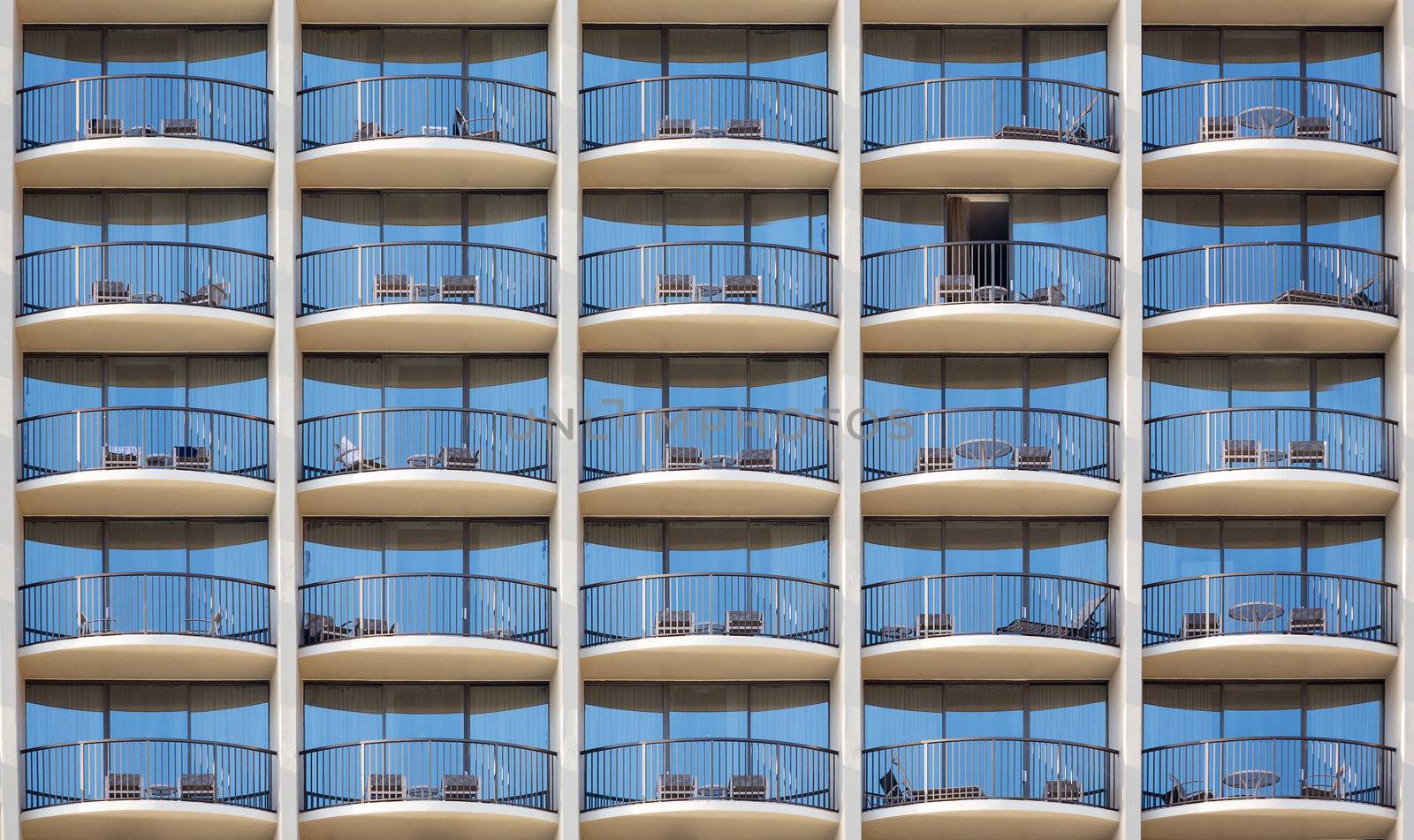Pattern of hotel room balconies in modern building with one patio door open