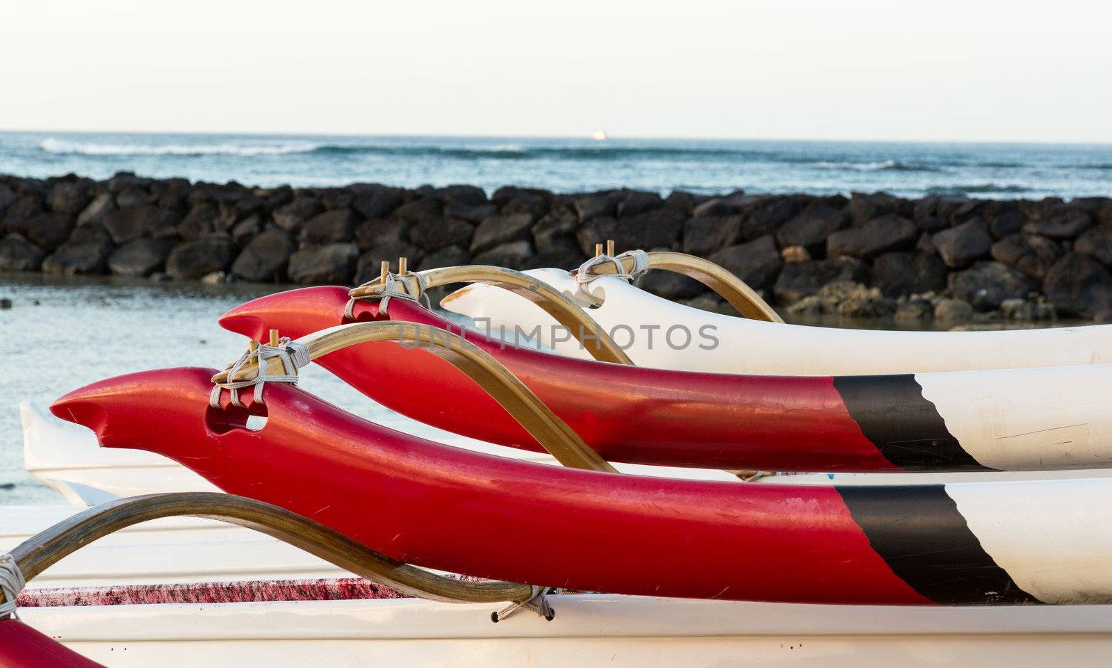 Early morning sunrise at dawn illuminates outrigger of traditional Hawaiian canoe in Waikiki Beach area of Oahu in Hawaii