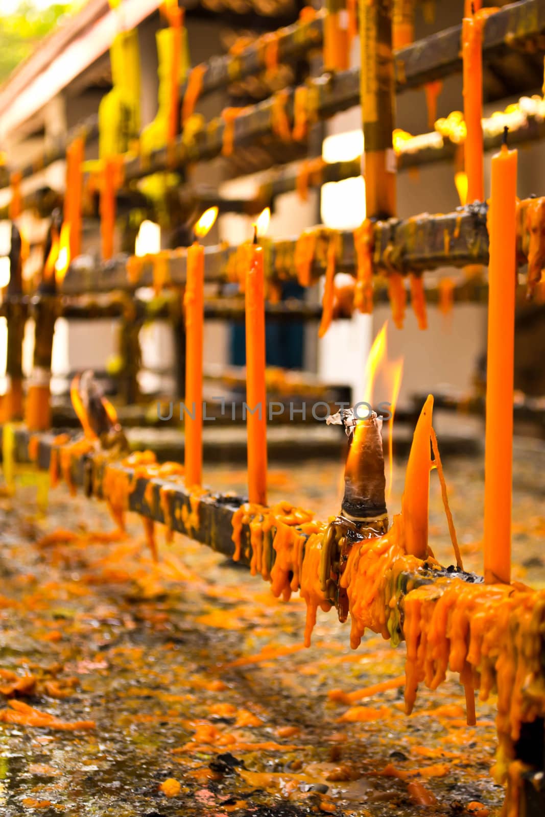 Burning candles in temple by Thanamat
