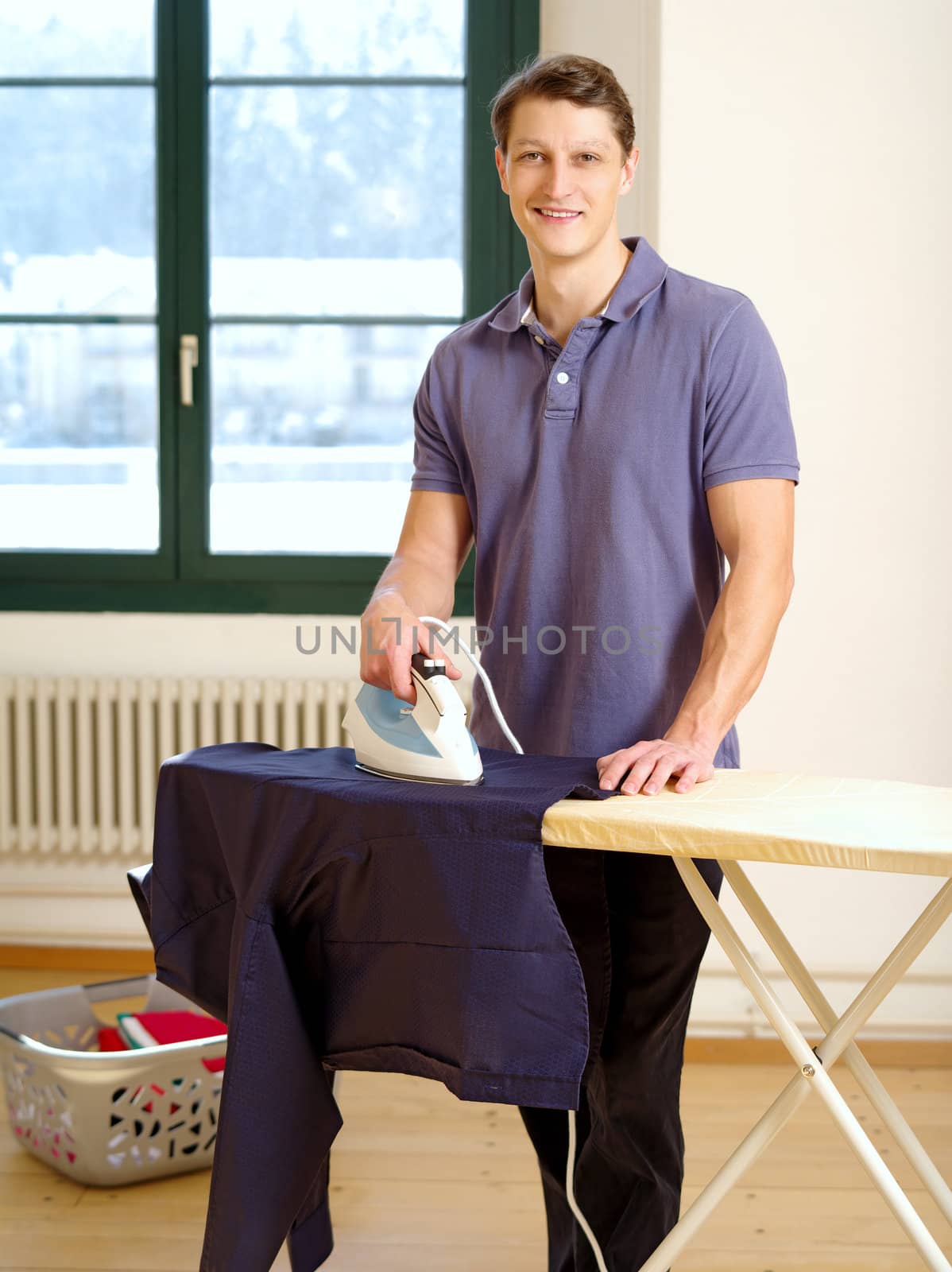 Photo of an attractive male ironing a shirt.