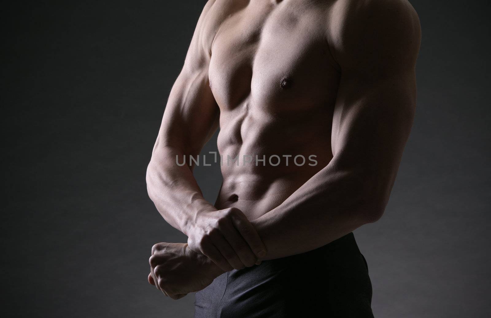 A shirtless male of a healthy fit young guy flexing his biceps