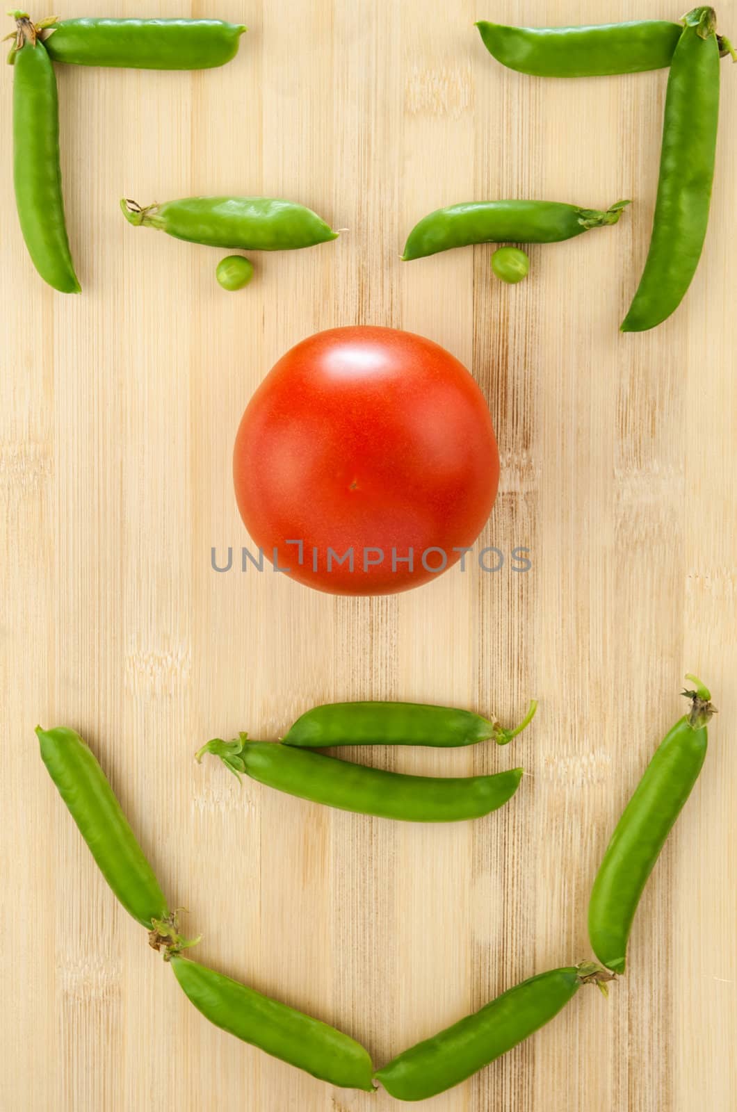 tomato and green peas laid out on a table in the form of face