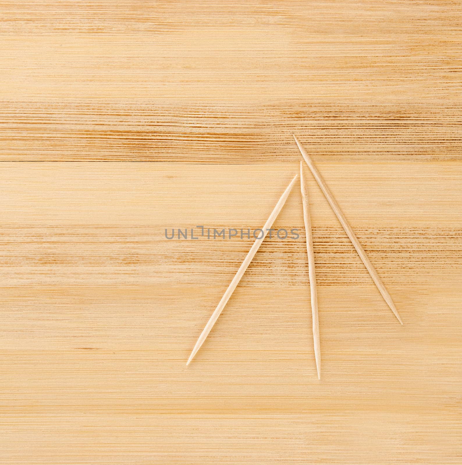 three toothpicks on a light wooden table