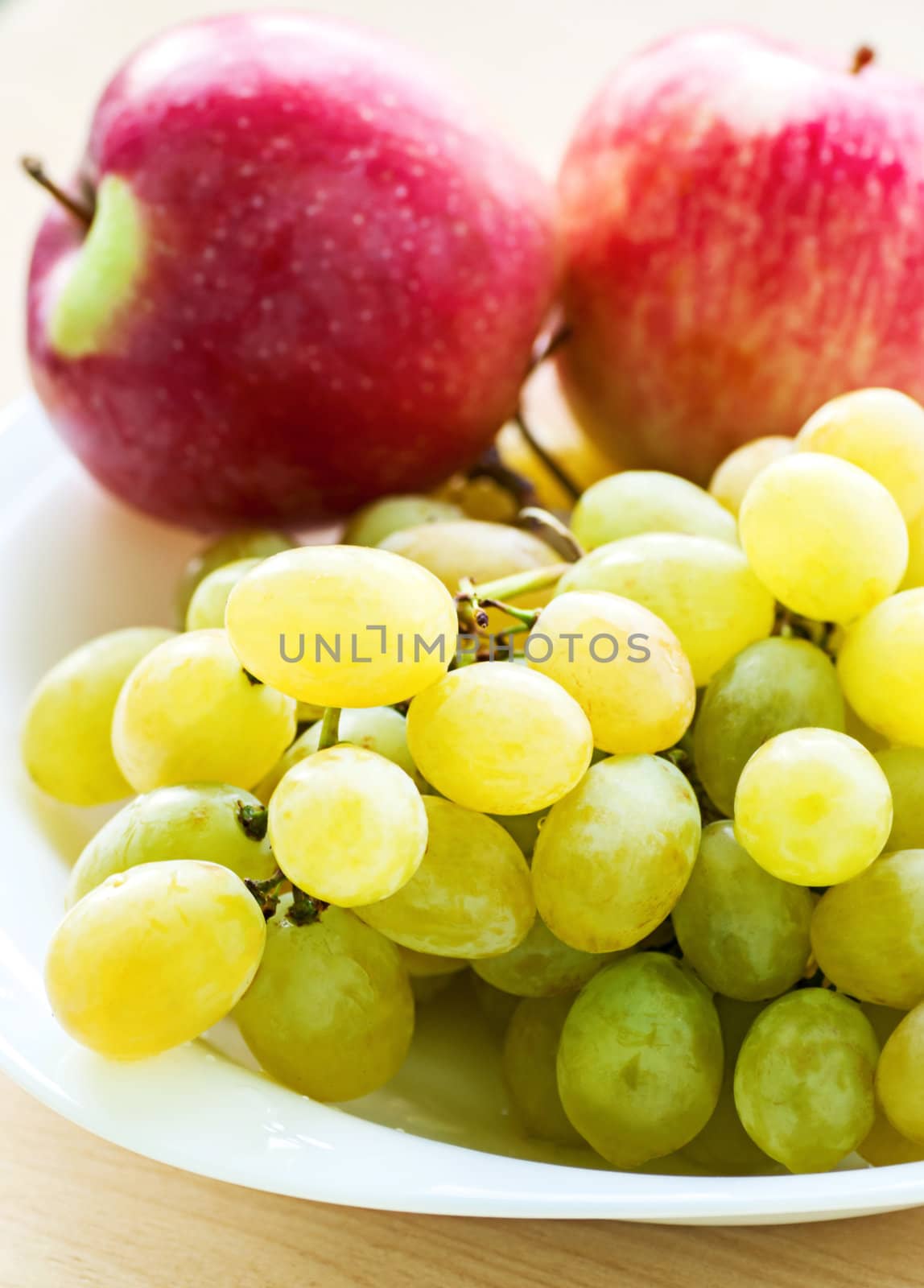Apple and grape fruit on dish, on white background