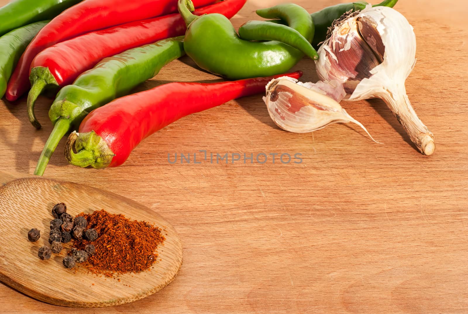 hot chili peppers, garlic and spices on wood board by Zhukow