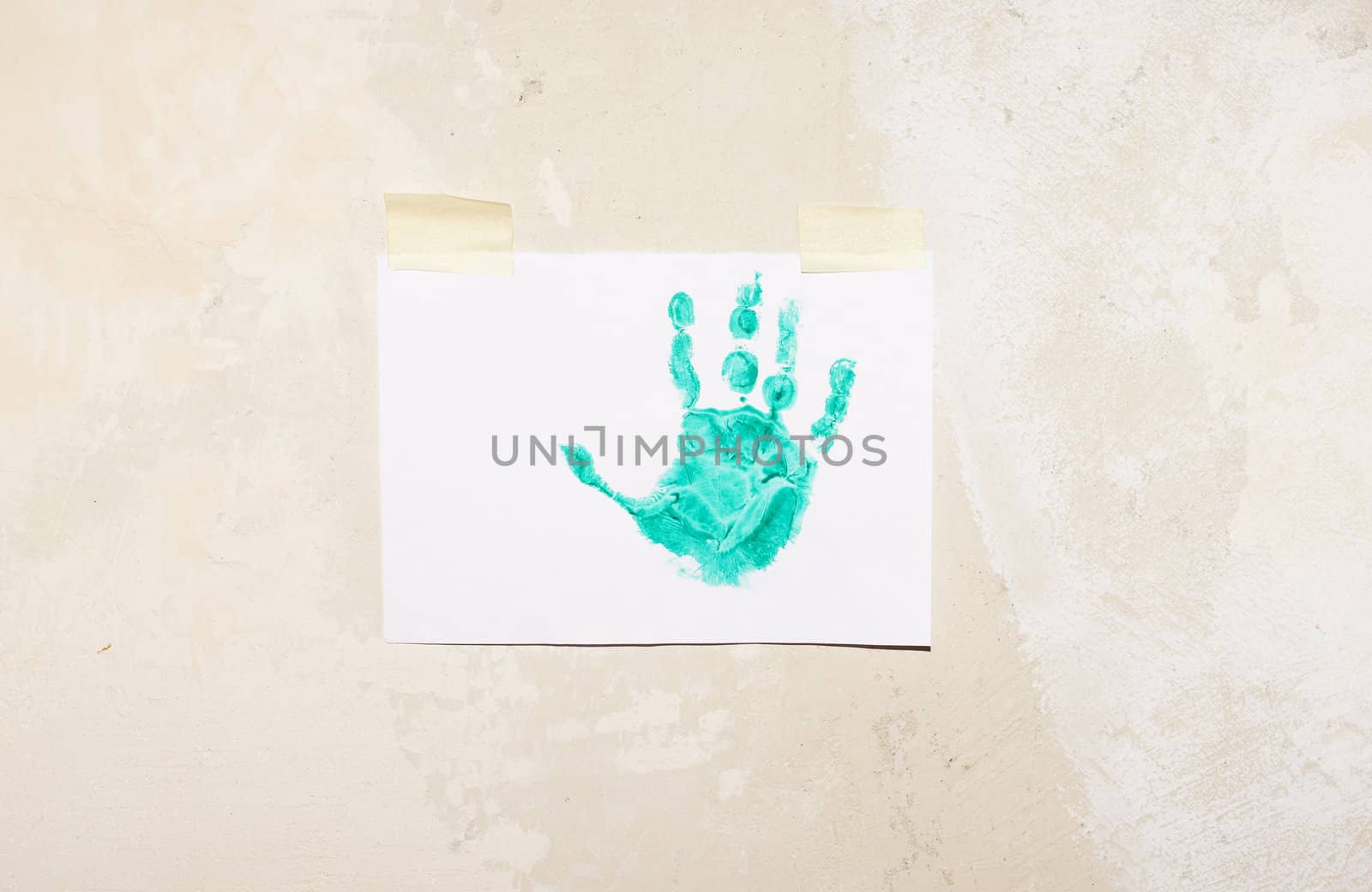 Imprint child hands on sheet of paper glued on the wall putty