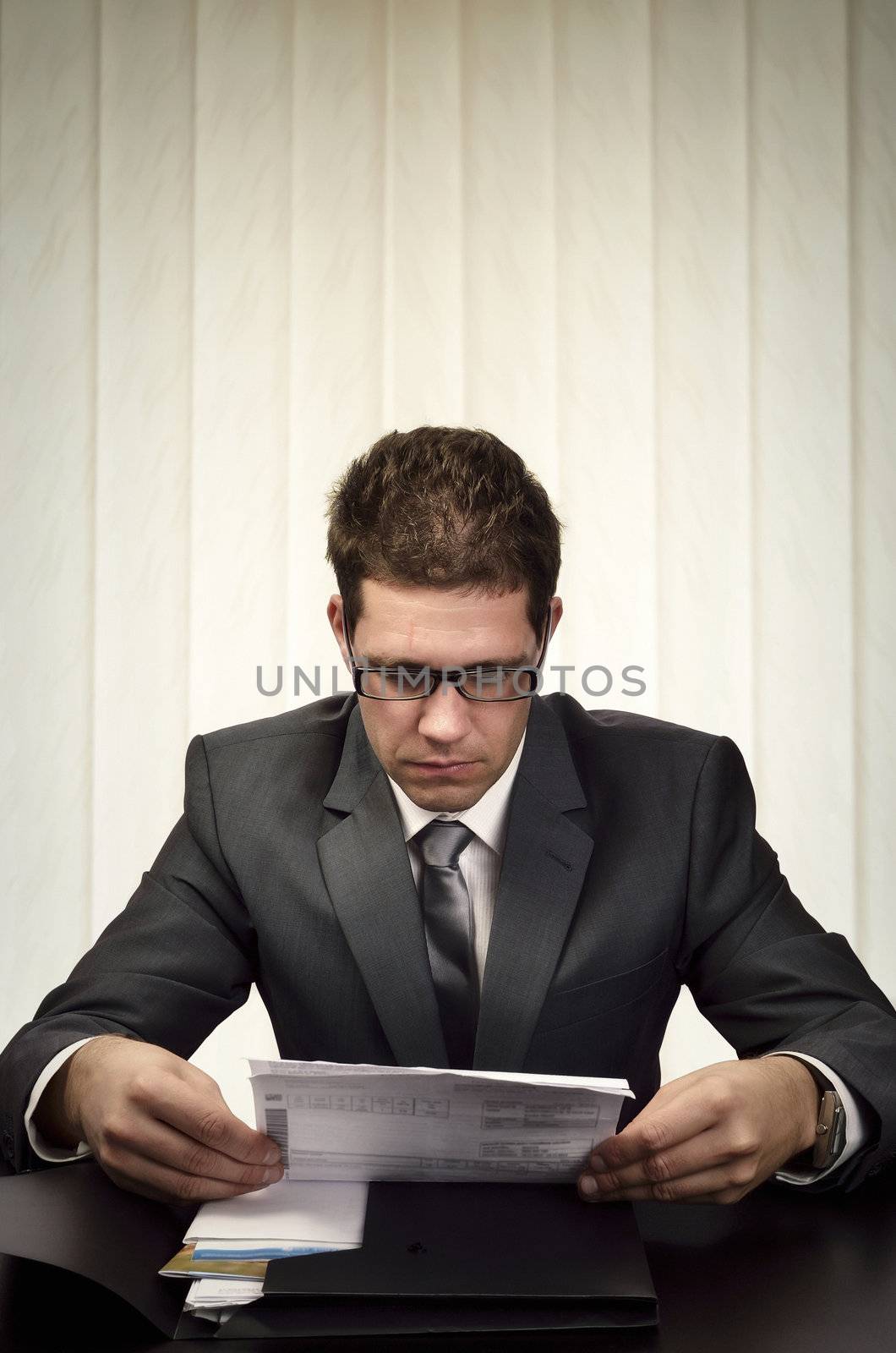 Businessman sitting in his office  attentively reading some document. 