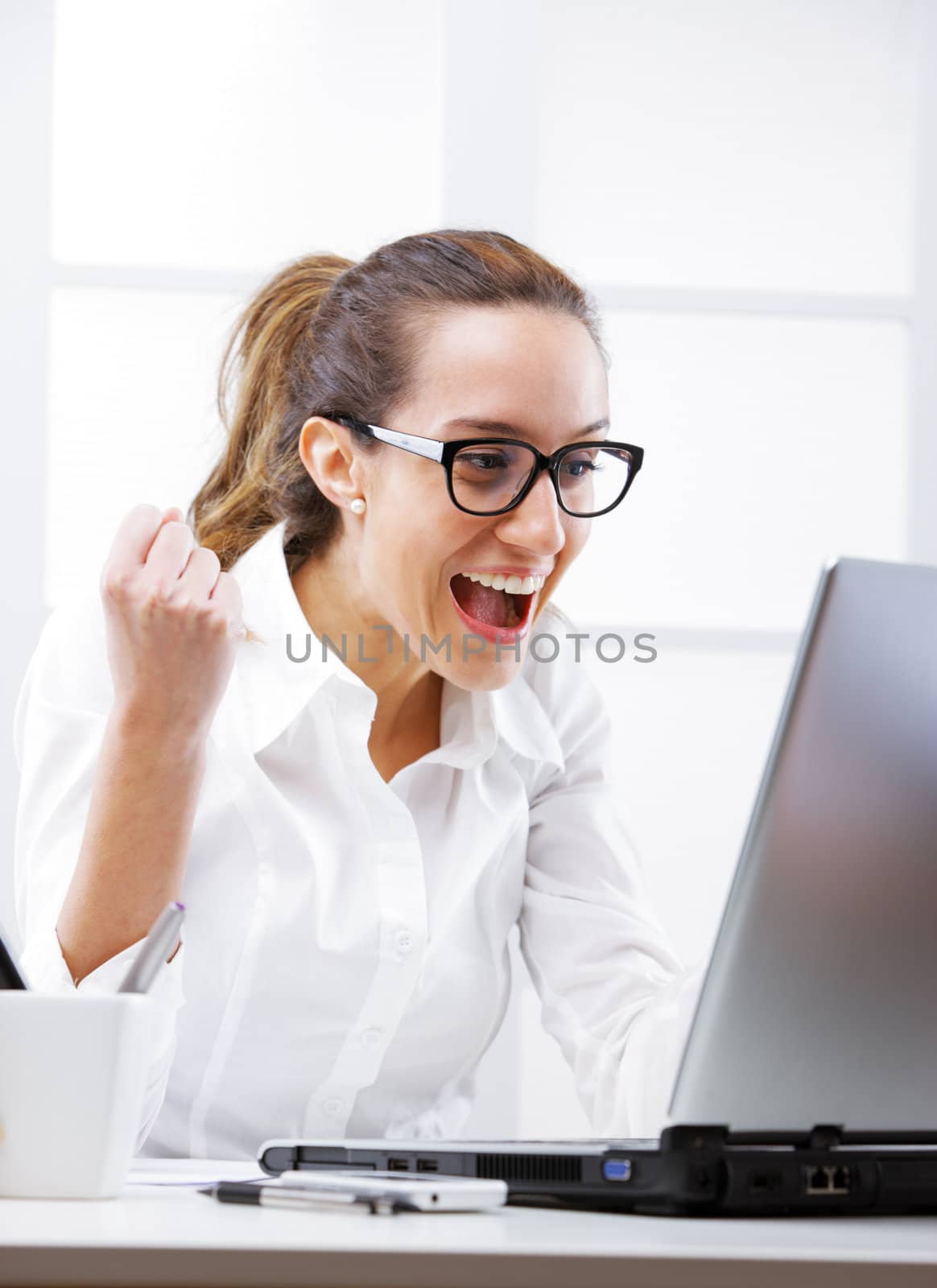 Young businesswoman cheering, screaming at laptop