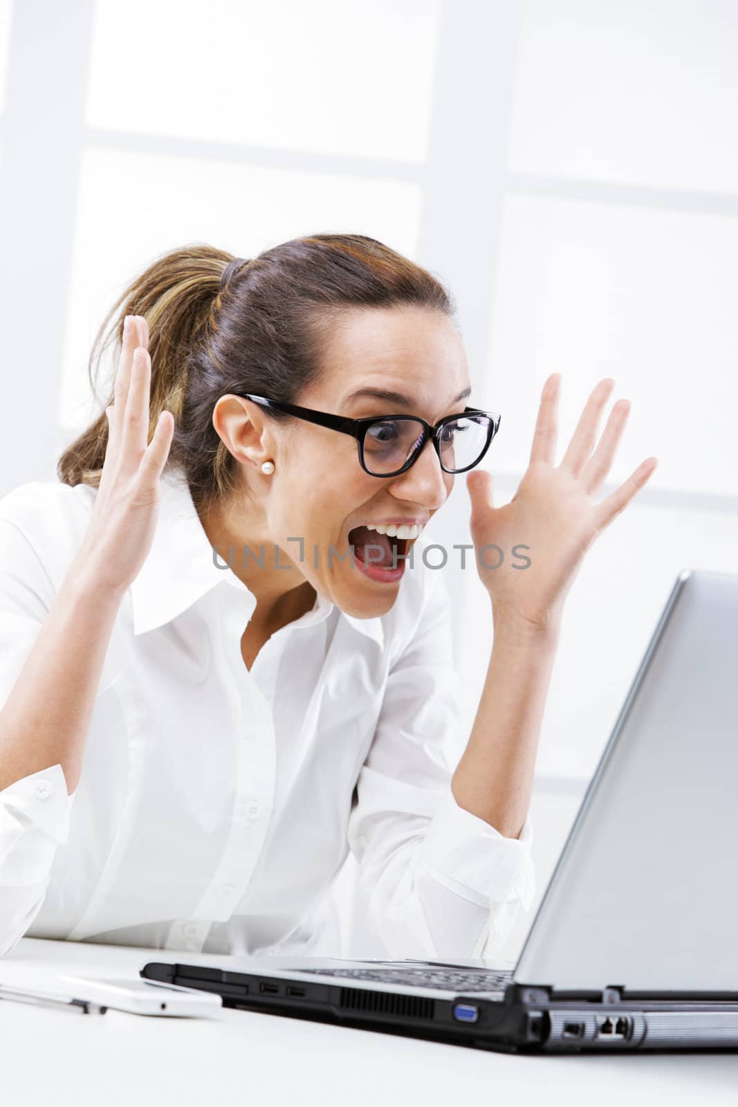 Young businesswoman cheering, screaming at laptop