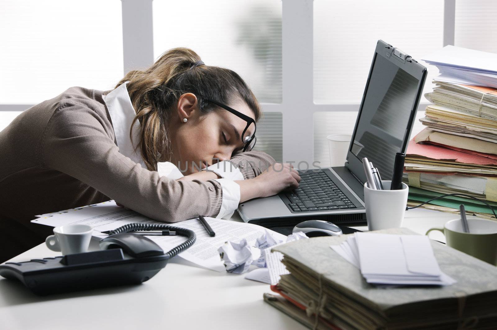 Tired businesswoman sleeping on the desk, in front of the computer screen.