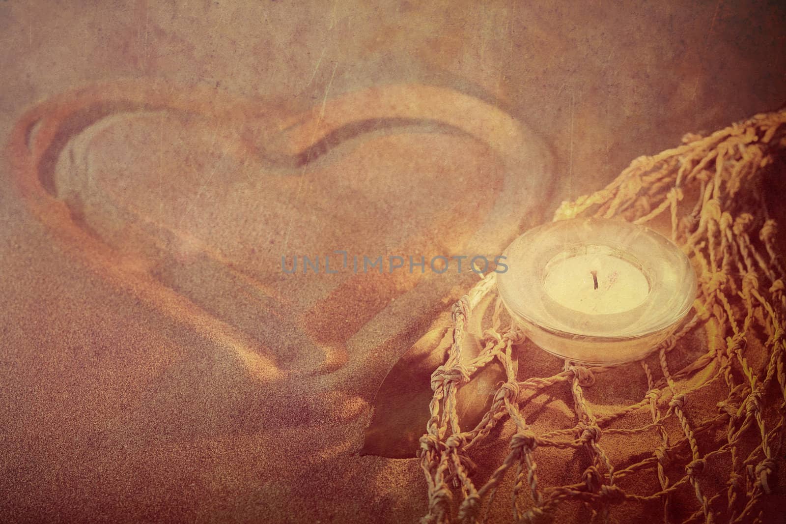 retro toned heart on yellow soft sand with lighted candles