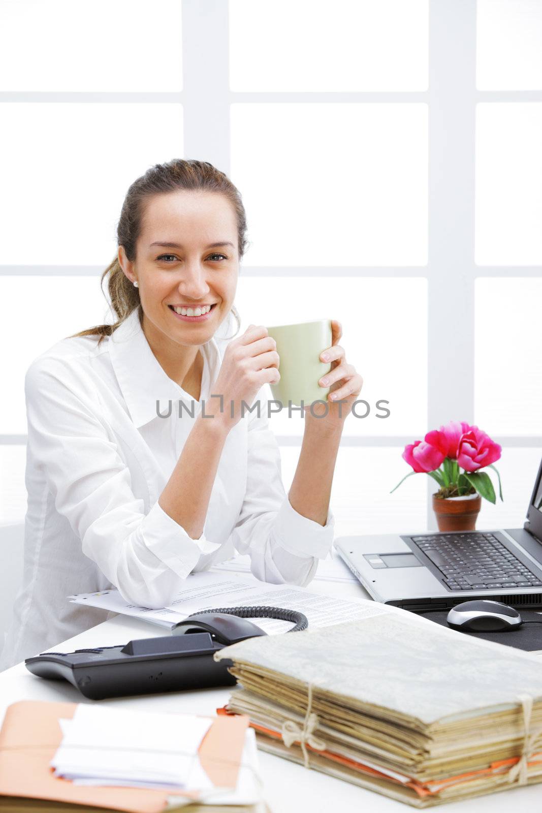 Business woman sitting at the office table with cup of coffee and laptop