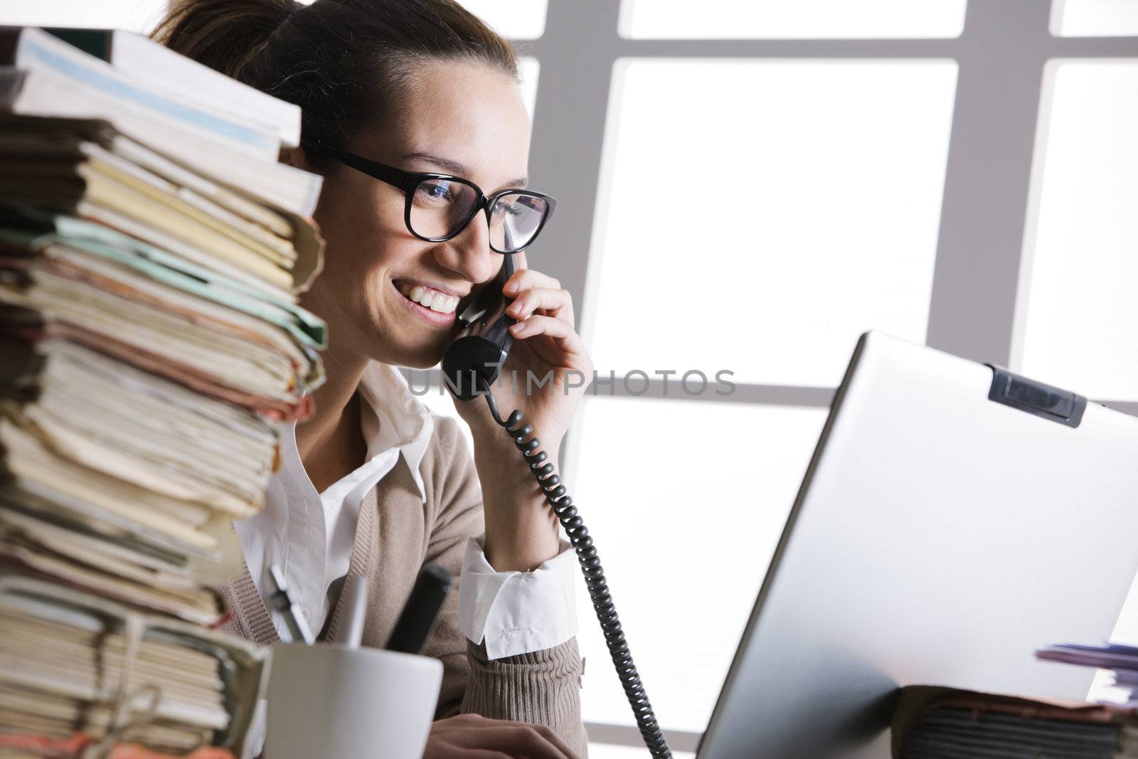 Beautiful young woman working in office and making a phone call