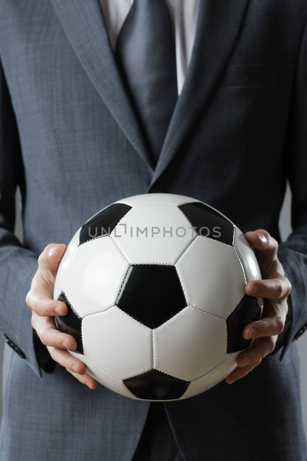 Elegant businessman holding a soccer ball, close up