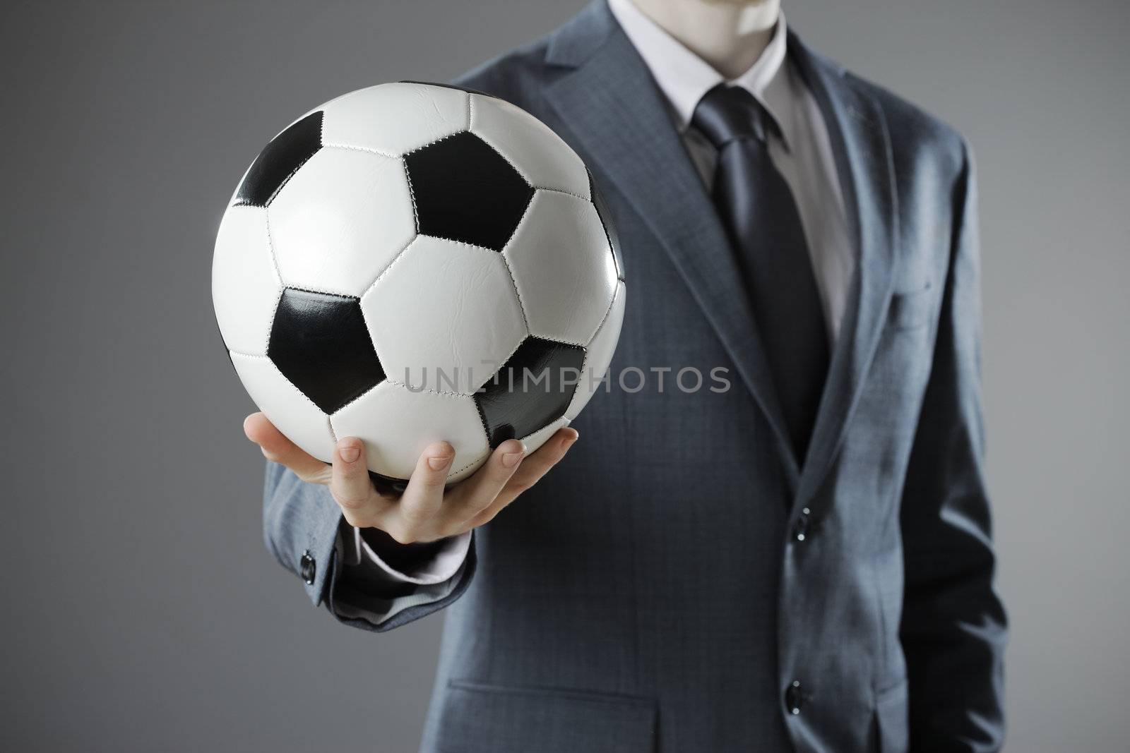 Elegant businessman holding a soccer ball, close up