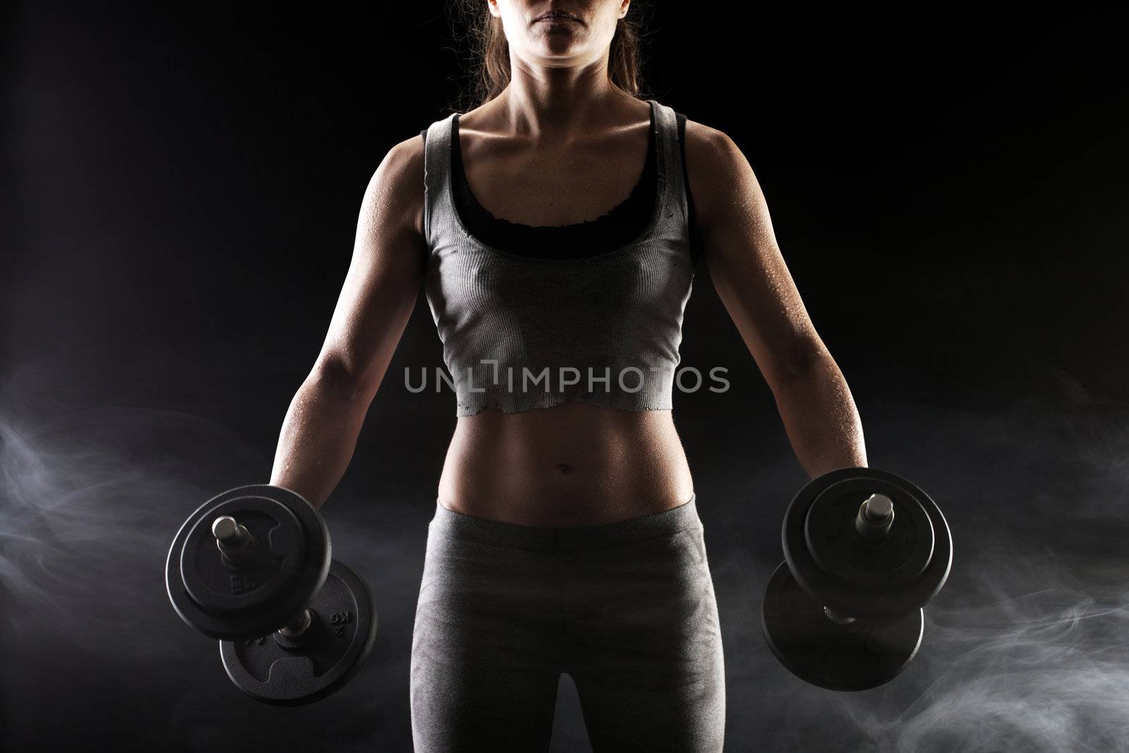 Young woman lifting the dumbbells