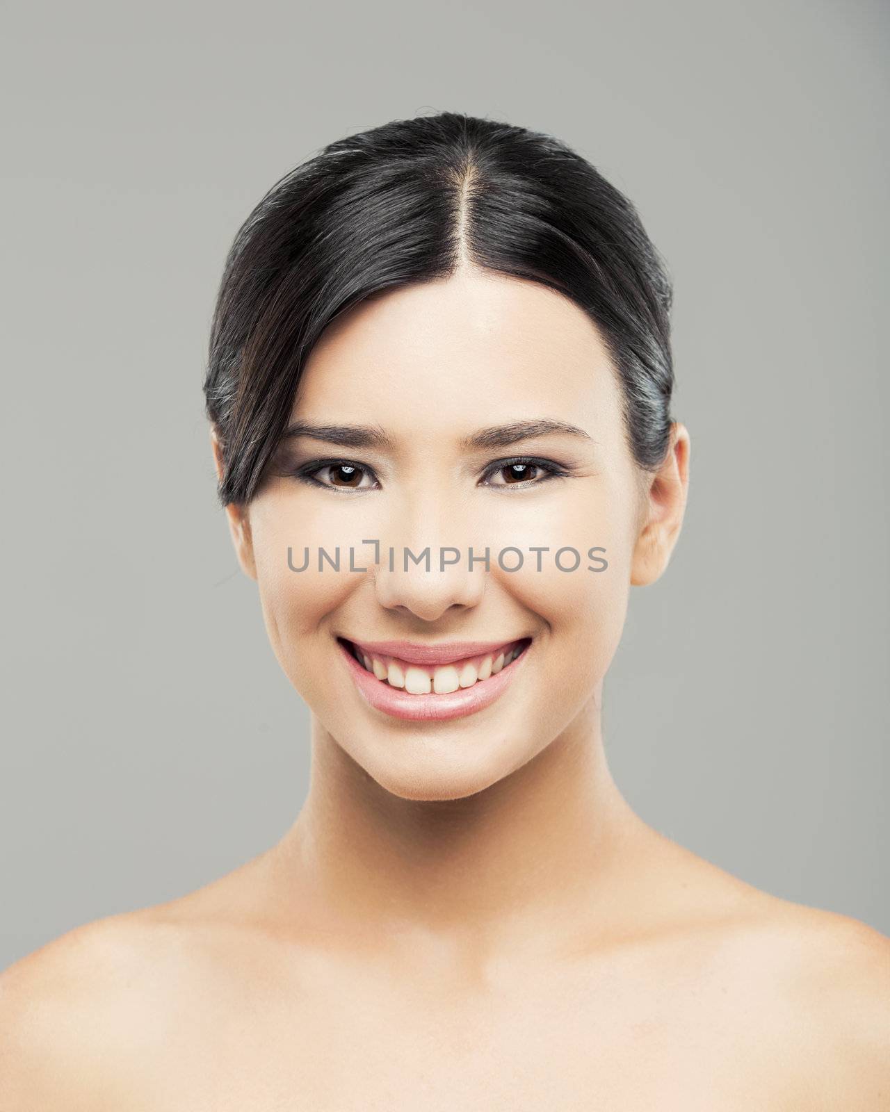 Beauty portrait of young asian woman smiling, over a gray background.