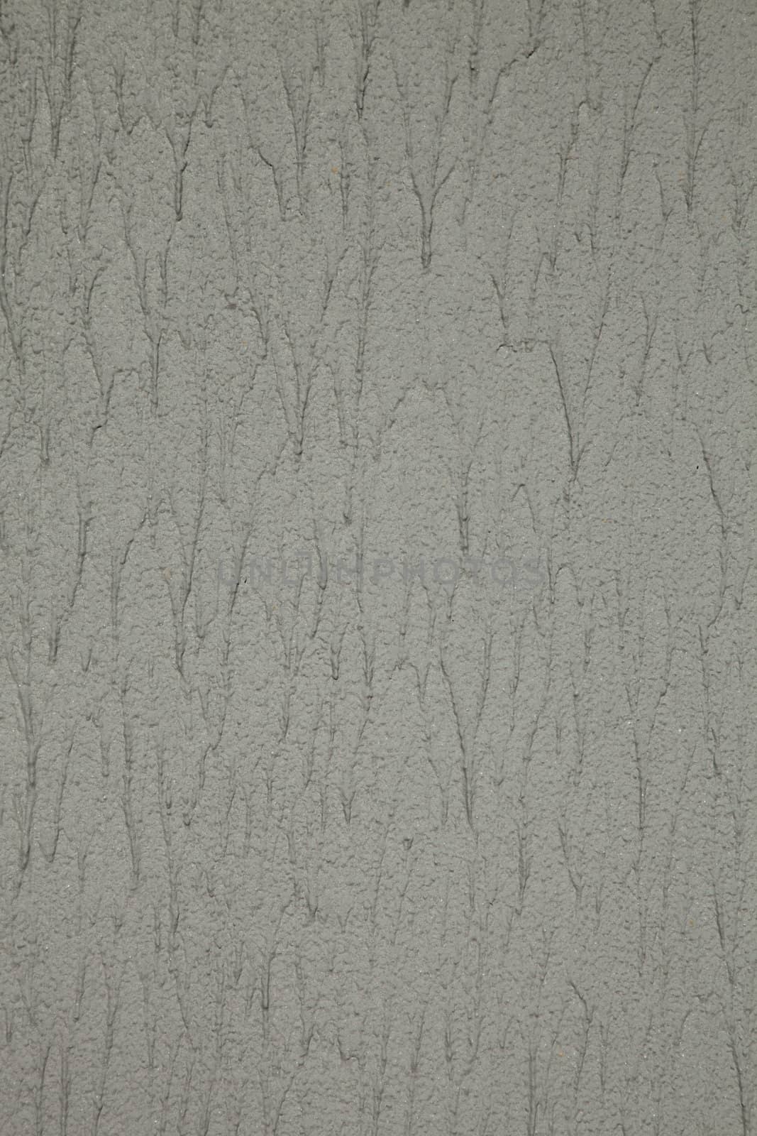 Wall with grey textured granular spray paint in excess with runs.