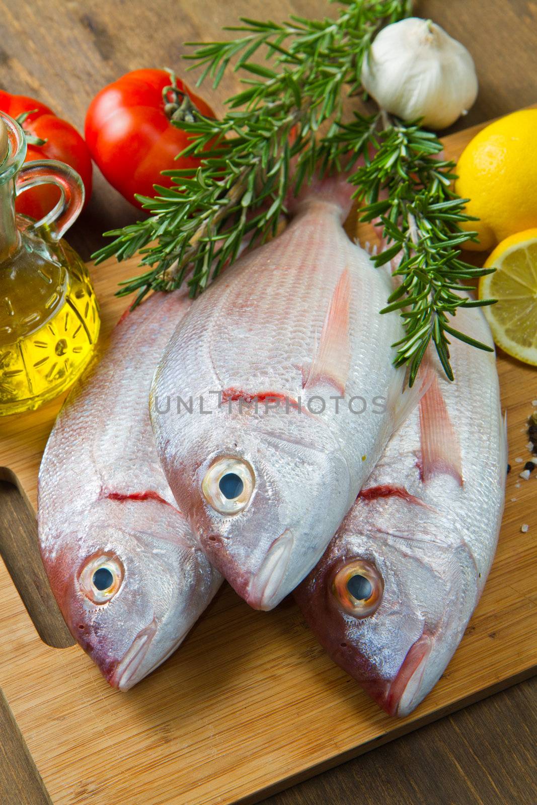 a group of sea bream with lemon and rosemary on wood table
