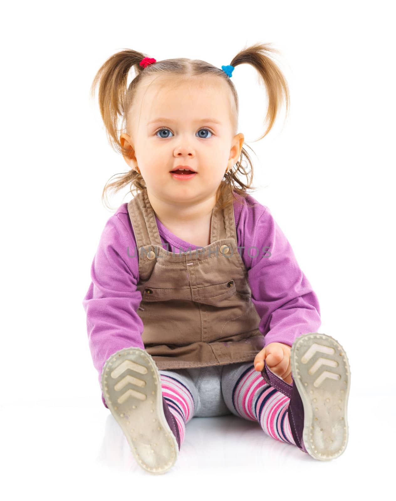Pretty little girl sitting on white background in studio. Vertical view